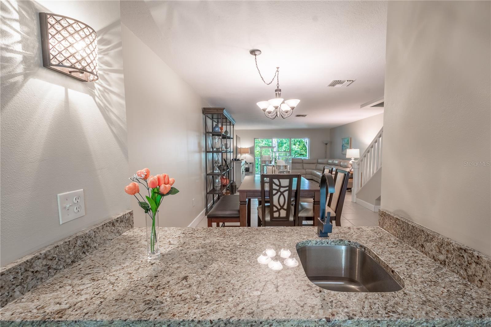 The wet bar, illuminated by a stylish wall sconce,  is open to the dining room.