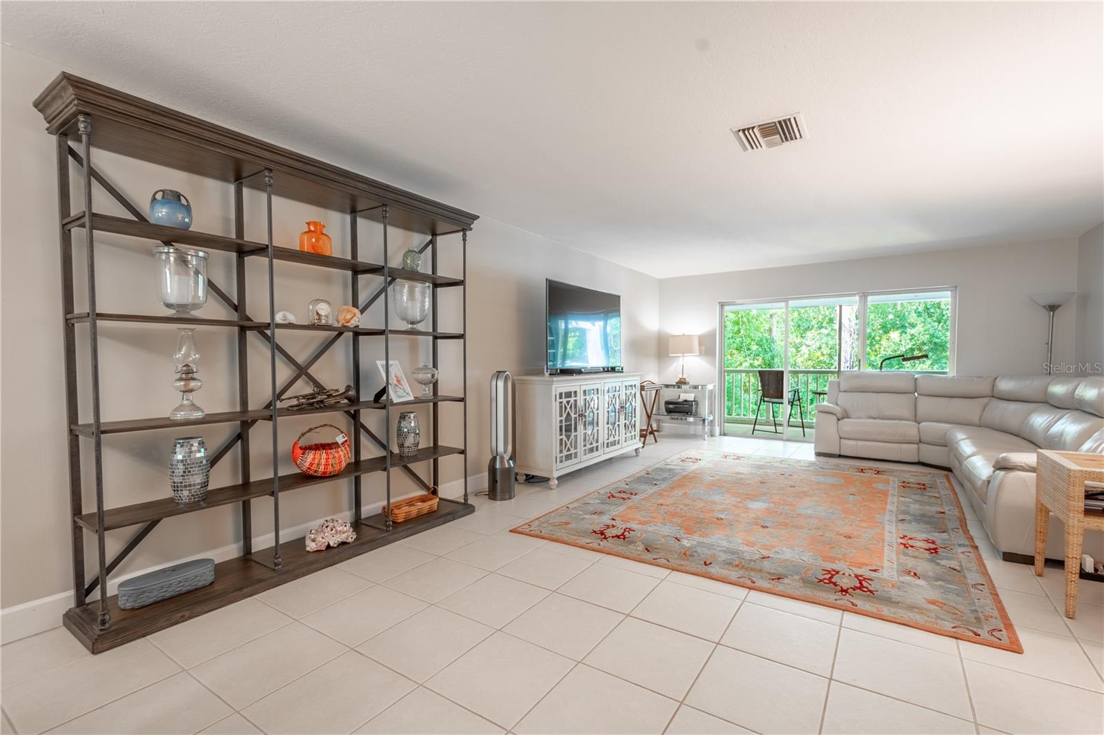 The 21' x 15' living room is expansive, with a neutral color palette, ceramic tile floor and sliding glass doors to the covered balcony.