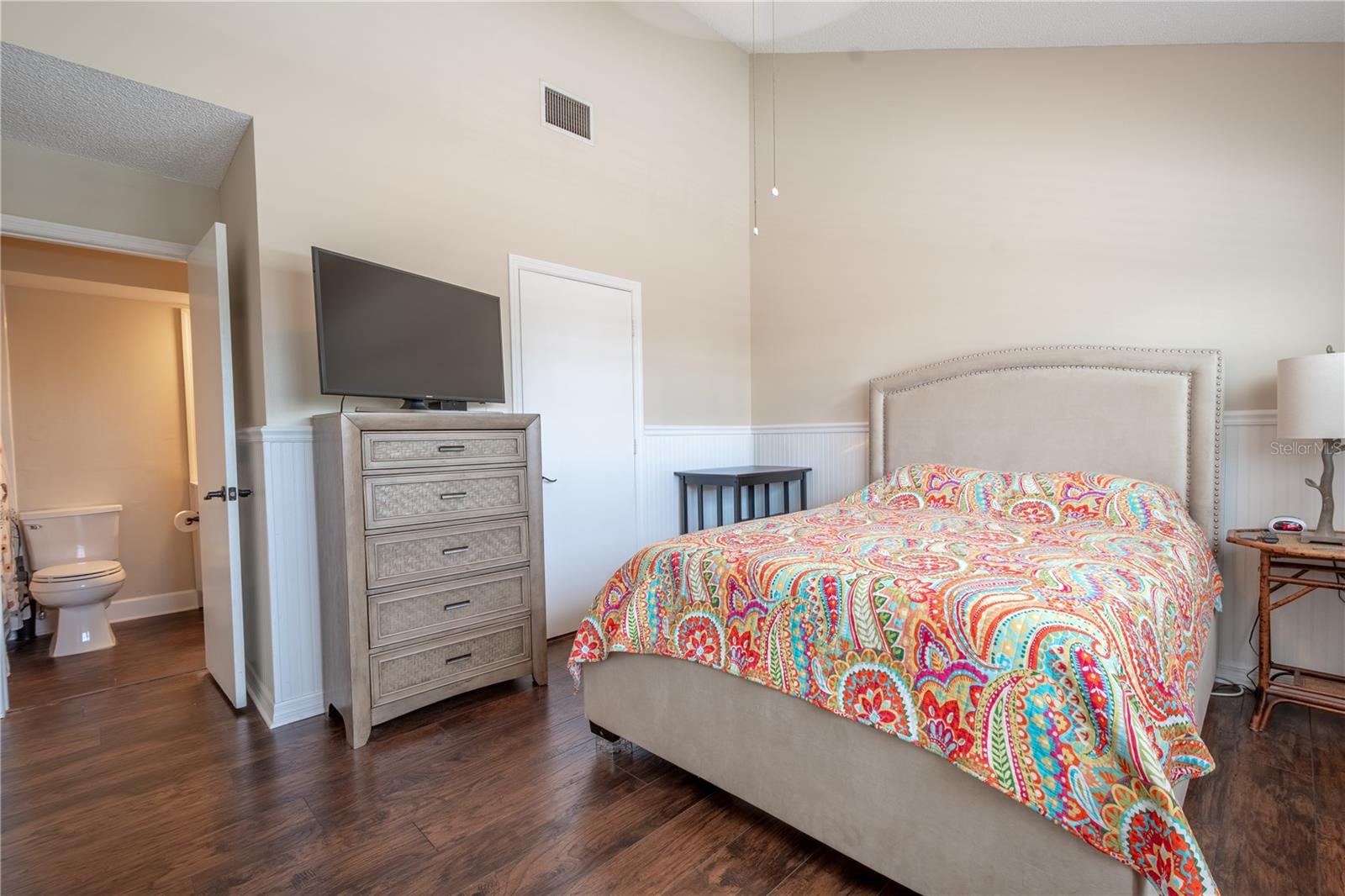 Bedroom 2 has a vaulted ceiling with a ceiling fan, vinyl (wood plank) flooring, and an ensuite bath.