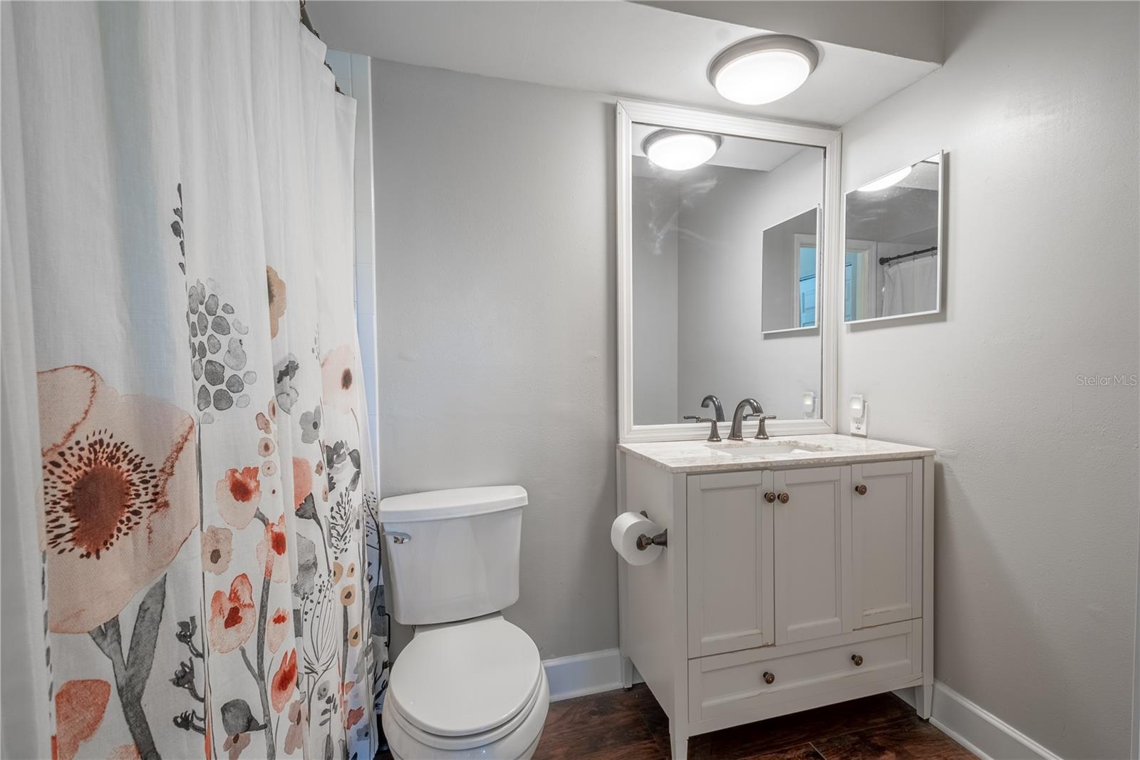 Bath 2 (ensuite) features vinyl (wood plank) flooring and a mirrored vanity with storage and a tub with shower.