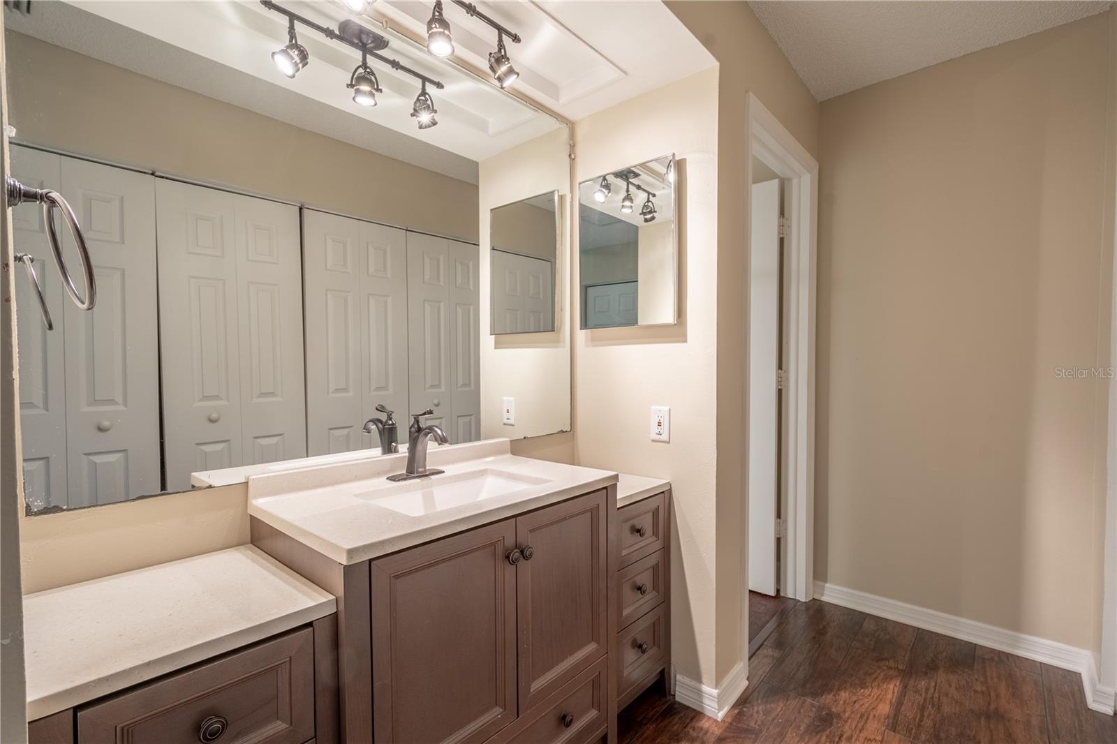 The primary bedroom ensuite features a mirrored vanity with storage and downlight fixture.