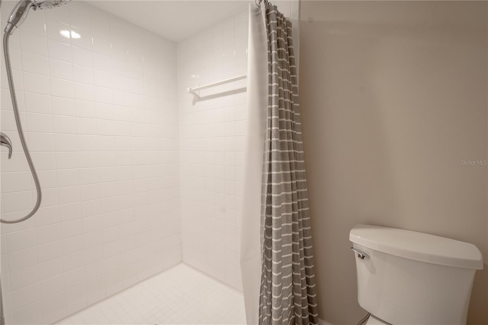 The primary bath features a large tiled, walk-in shower.