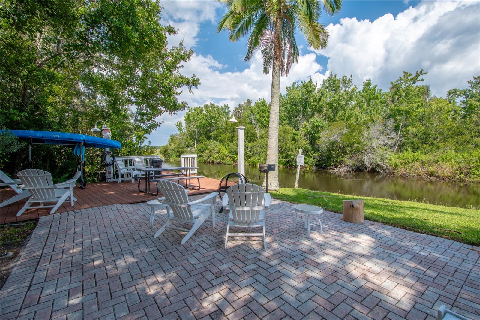 The  community features beautiful brick patio, shaded by trees and palms, with a serene water view.