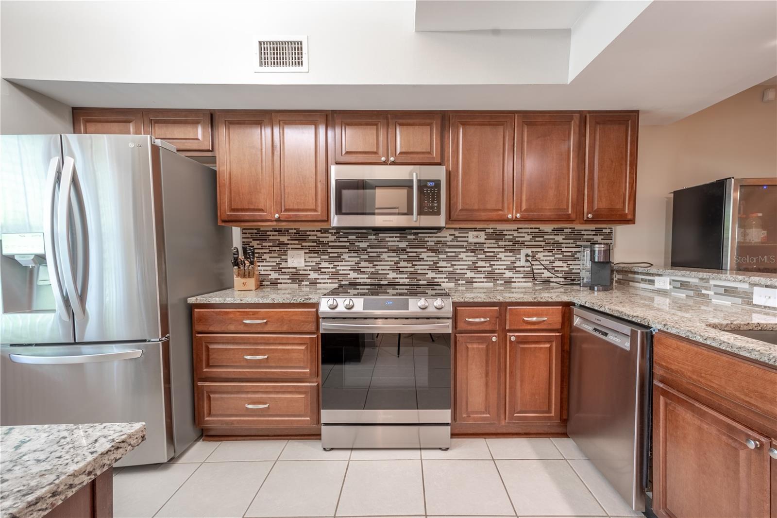 Spacious kitchen with granite counter tops, tile back splash and ceramic tile flooring.