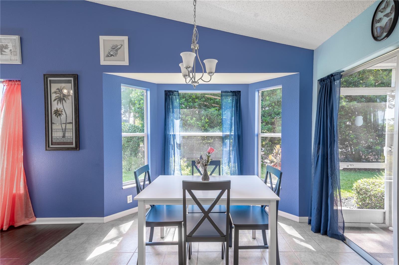 The breakfast nook sits beneath a chandelier in a bay window