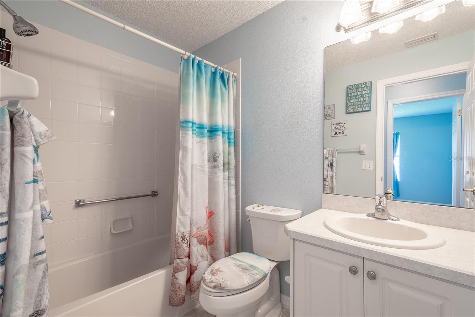 Bath 2 features a mirrored vanity with storage and downlight fixture, and a tiled tub with shower.