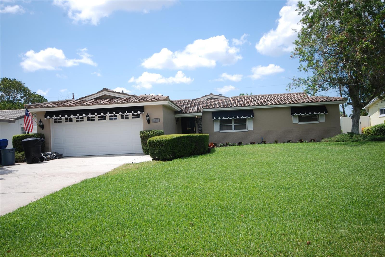 Front exterior showing tile roof and pretty shade awnings, and concrete drive.