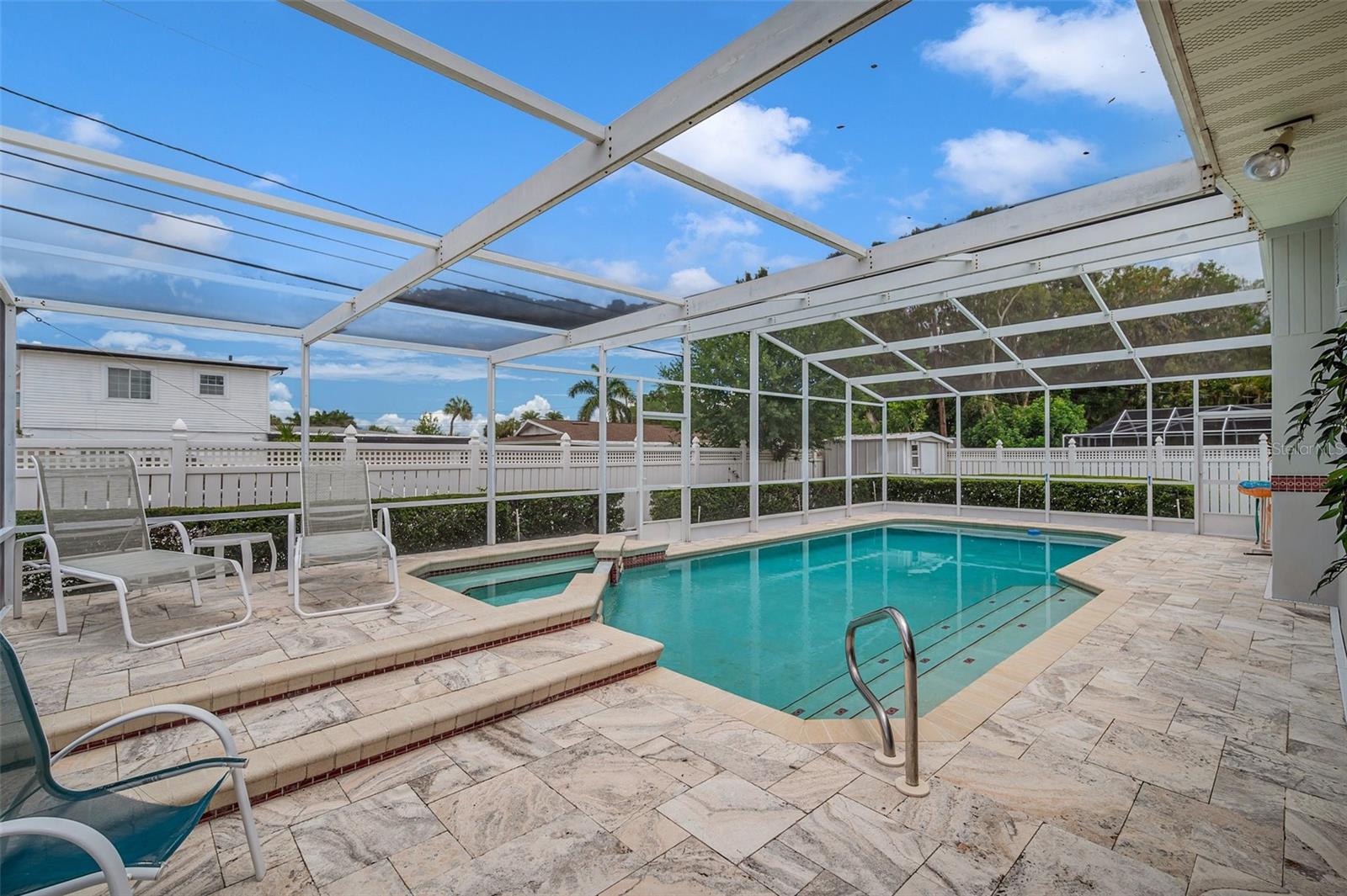 Large enclosed pool with spillover spa and huge travertine deck.