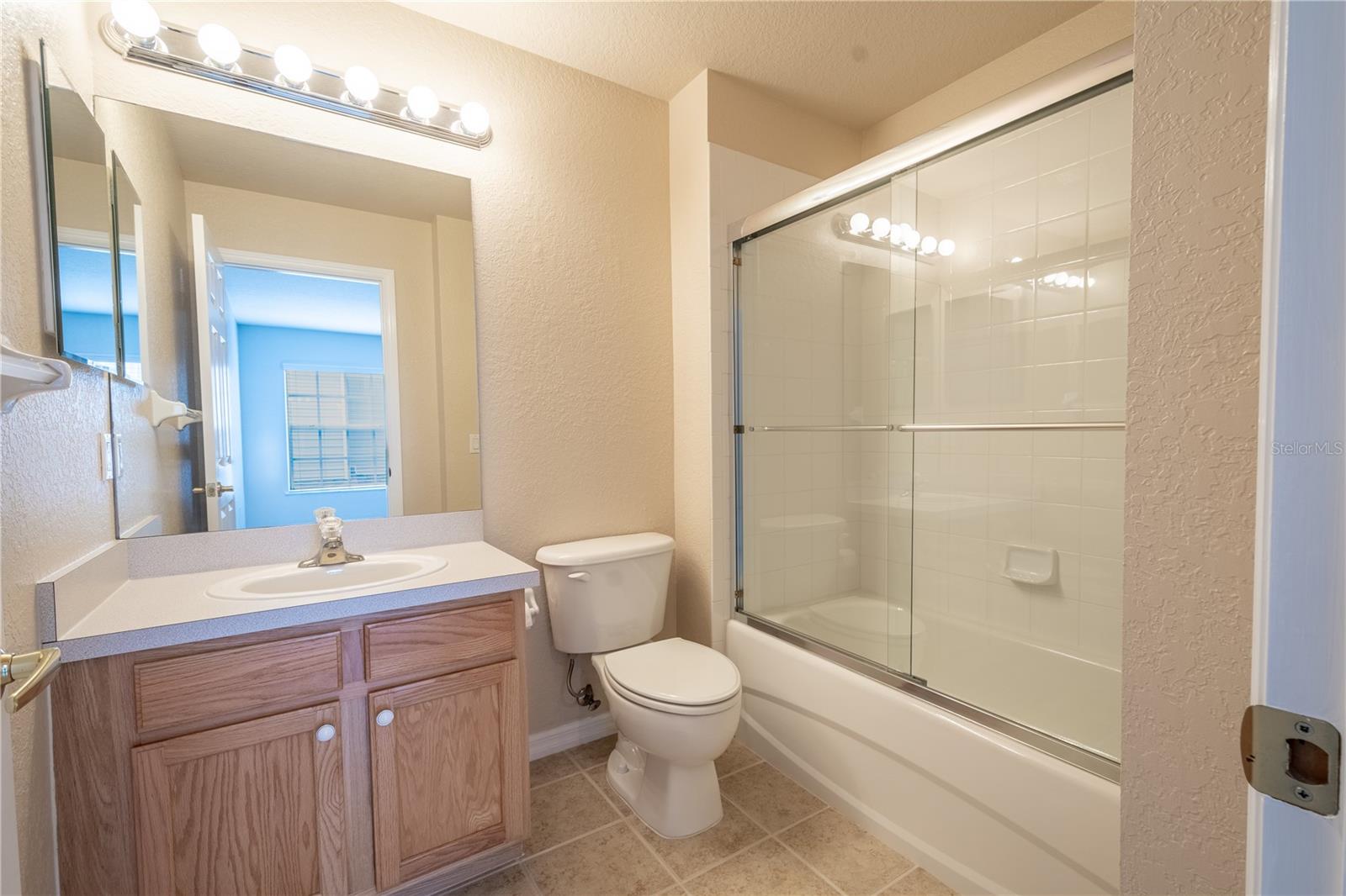 Bathroom 2 features ceramic tile flooring, a mirrored vanity with storage and a tiled tub with shower.