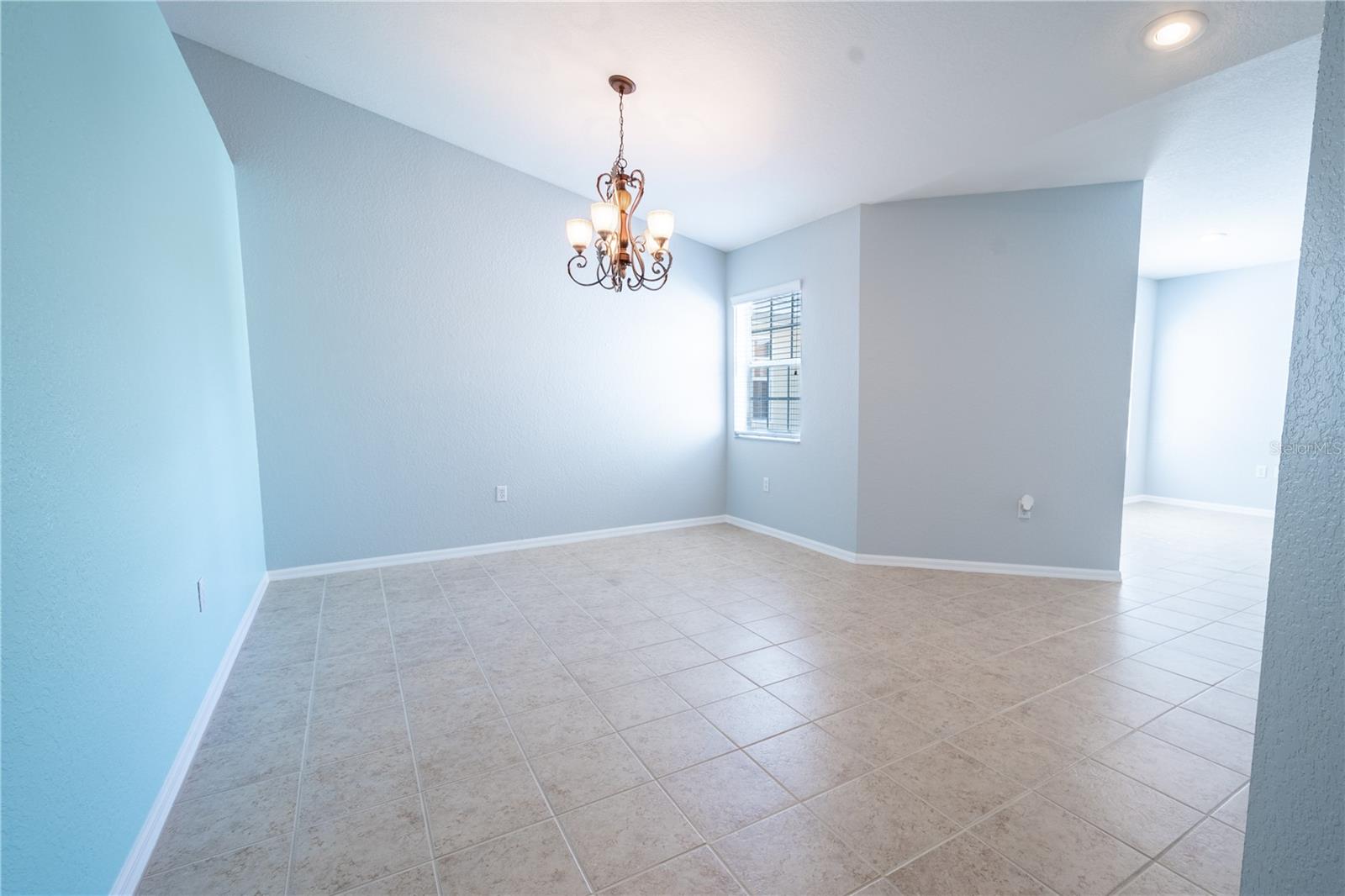 The spacious dining room features ceramic tile flooring, and a chandelier.