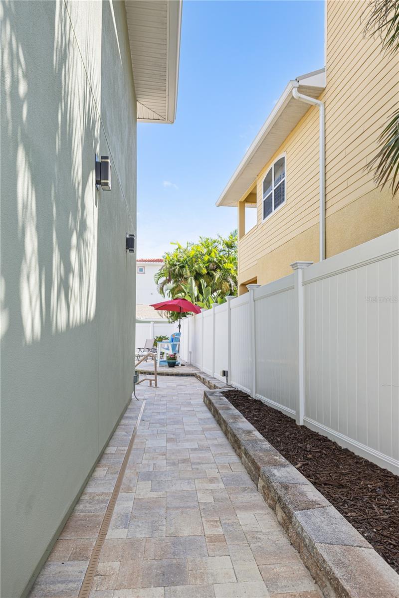 A garden-lined walkway from the pool area to the covered porch on the canal side of home.