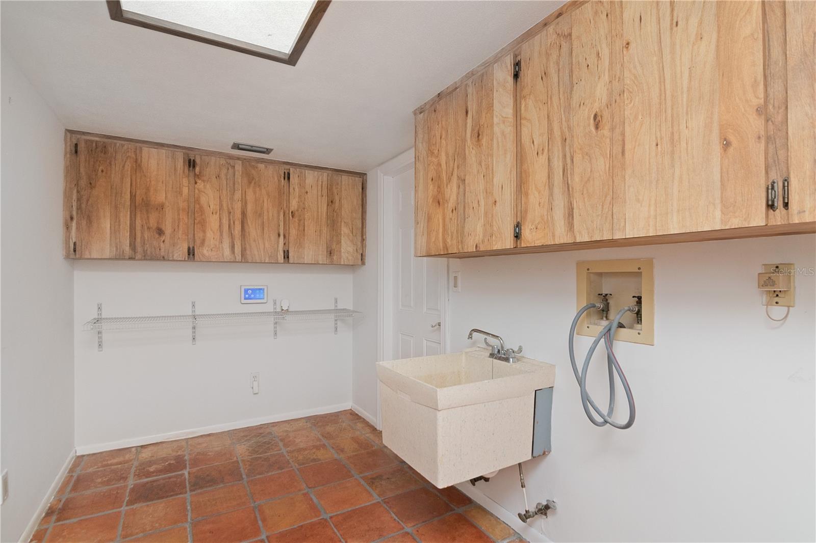 Laundry Room with door to 3-Car Garage featuring storage cabinets, utility sink, and ample space for a Washer and Dryer featuring New Paint and Tile Floor