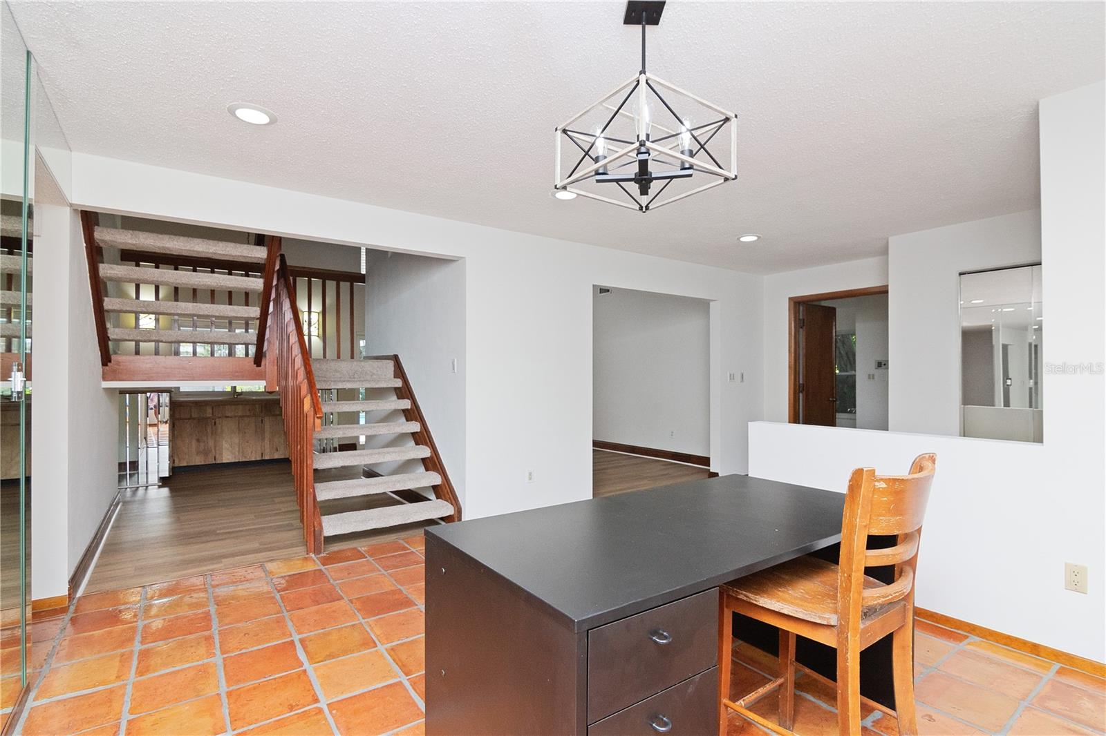 View of stairs from Formal Dining Room showing New Pendant Light, New Paint, New Carpet on Stairs, New Vinyl Under Stair and in Living Room and Tile Flooring