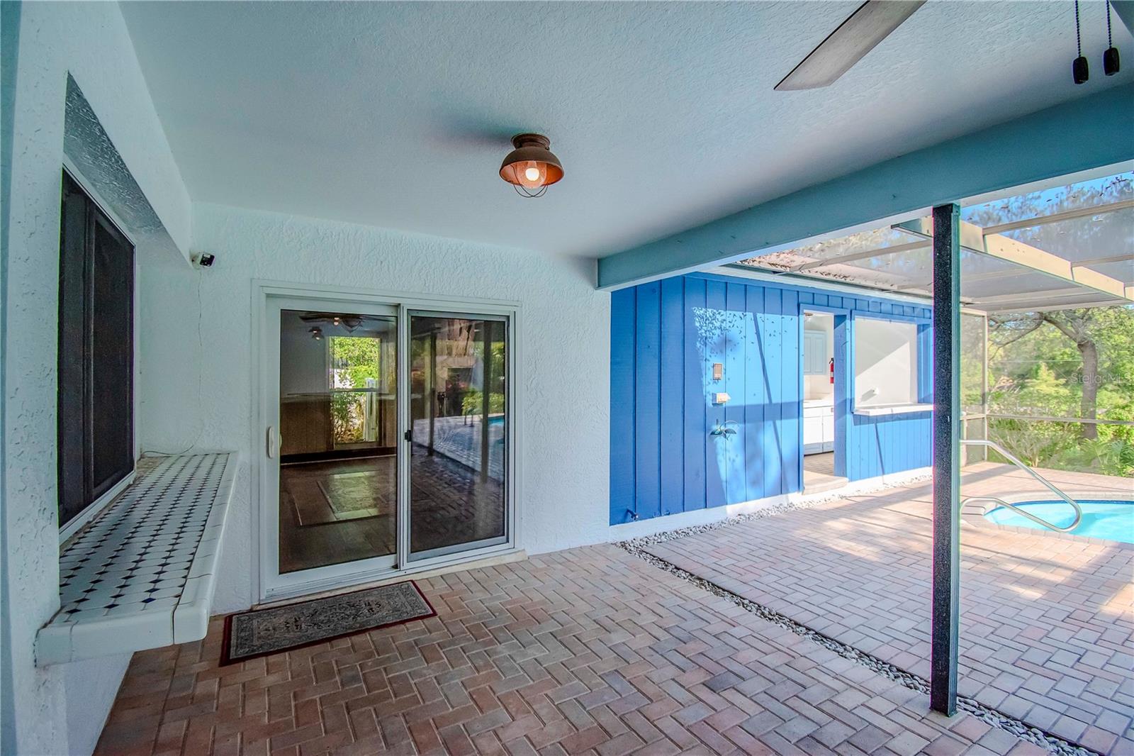 Outdoor Covered Porch with Window and Tile Bar (Opens to Wet Bar), Pavers and View of Outdoor Kitchen and Bar