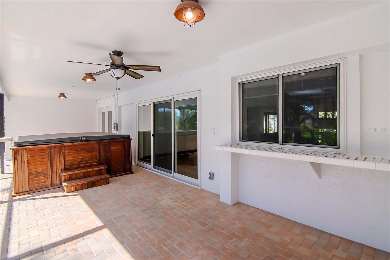 Outdoor Covered Porch with Hot Tub, Window and Tile Bar (Opens to Wet Bar), Pavers and Newer Lighting and Lighted Ceiling Fan