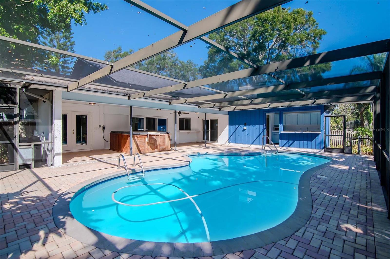 Screened in Pool with Pavers and view of Outdoor Kitchen and Hot Tub