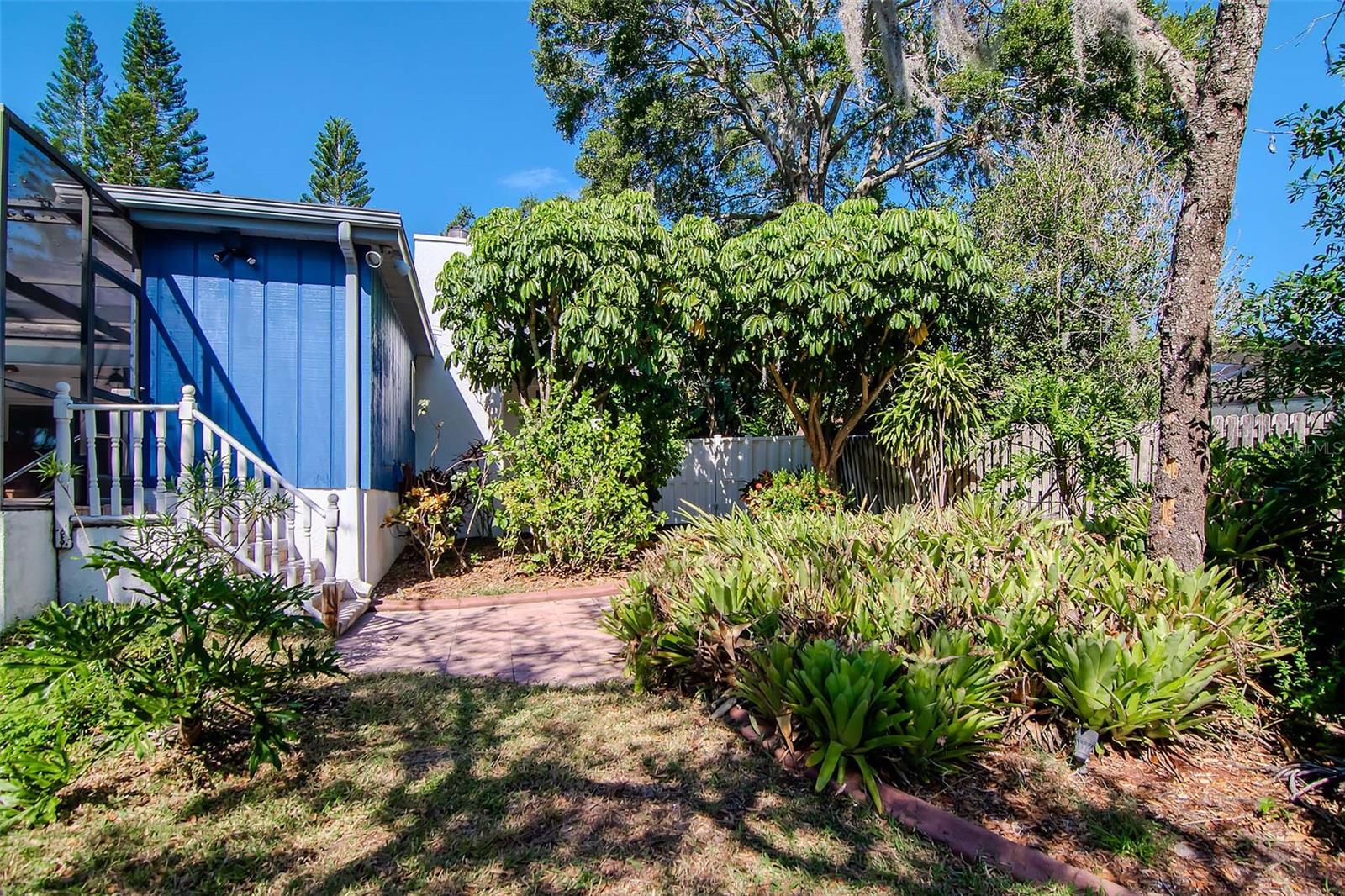 Stairs to Elevated Screened Lanai with Pavers and Lush Mature Landscaping