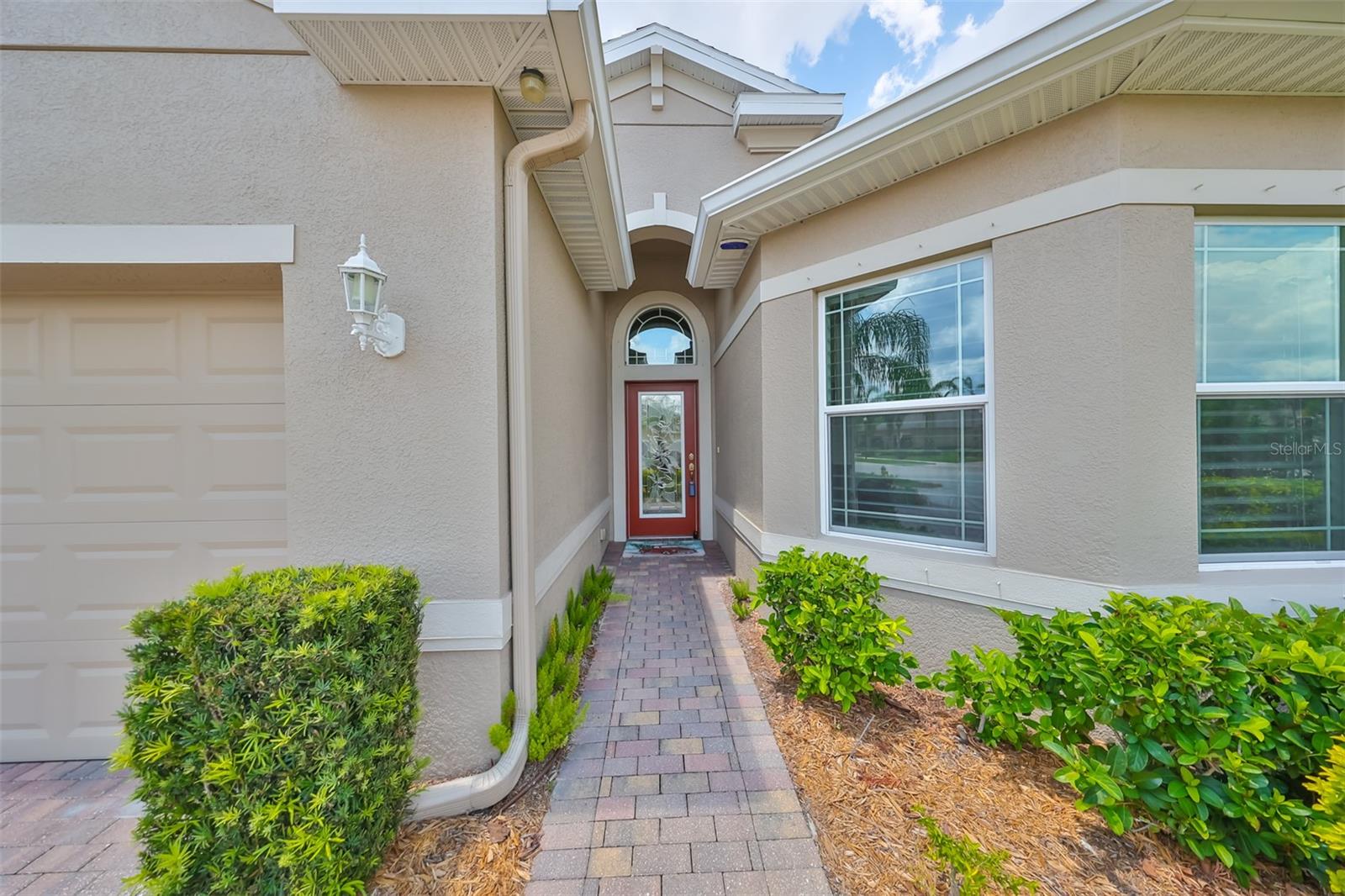 Lovely paved walkway to the hurricane impact glass front door welcomes you home.  Notice the gutters that help to keep the water from the foundation.