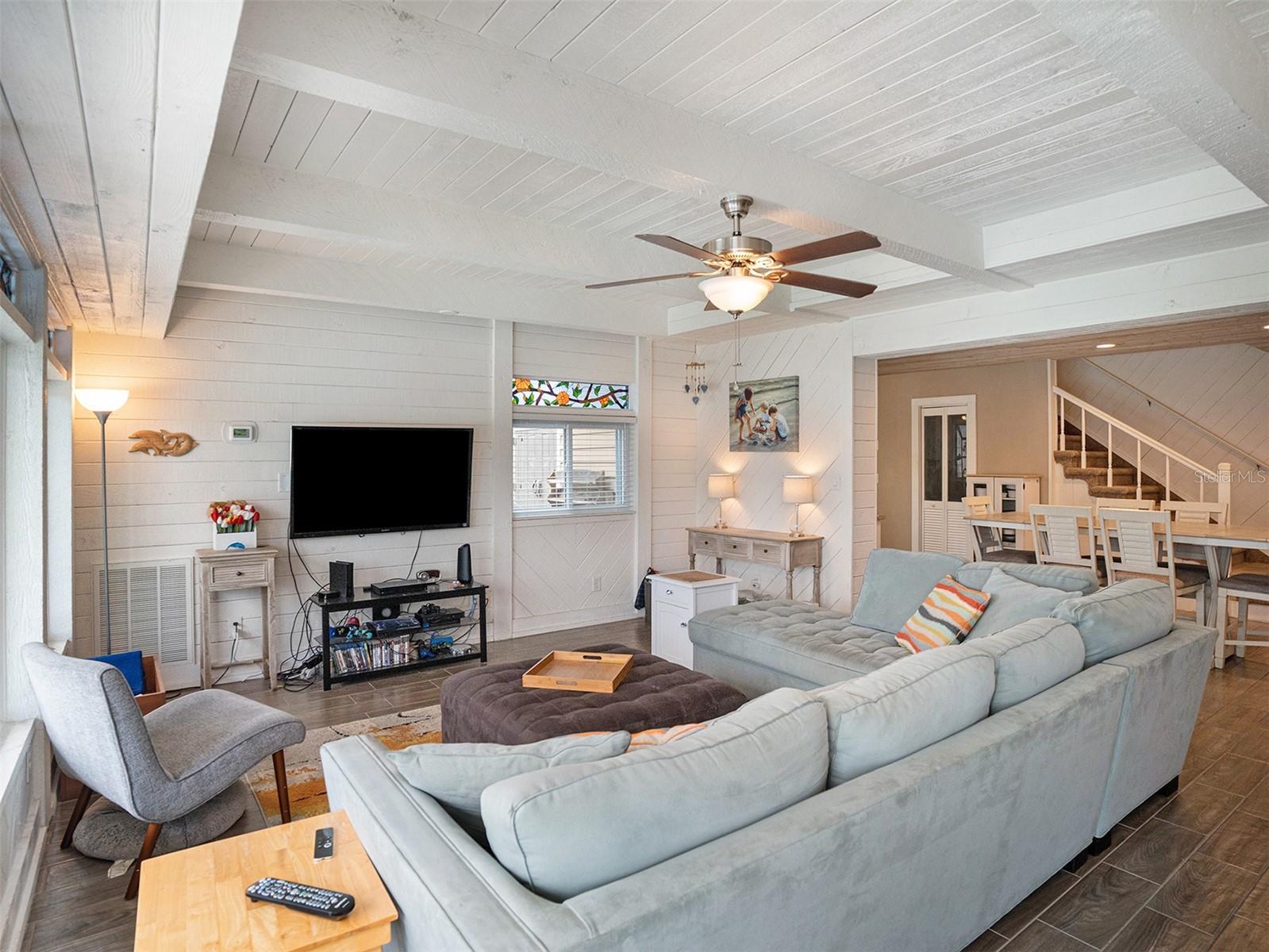 Family room with beamed ceiling, fireplace, and tons of natural light showcasing the pool and canal.