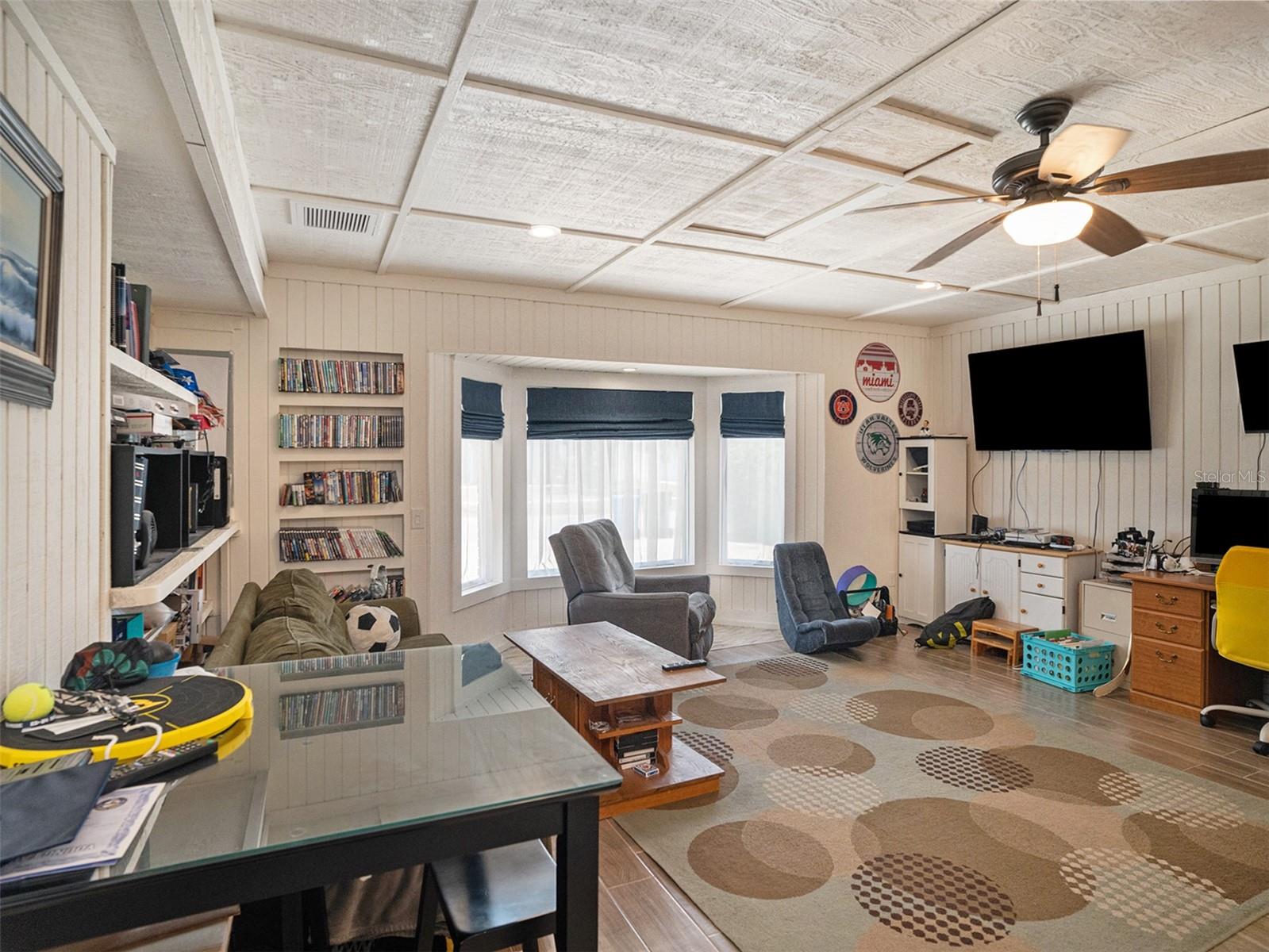 Family room with beamed ceiling, fireplace, and tons of natural light showcasing the pool and canal. with a wet bar keeps the fun going.