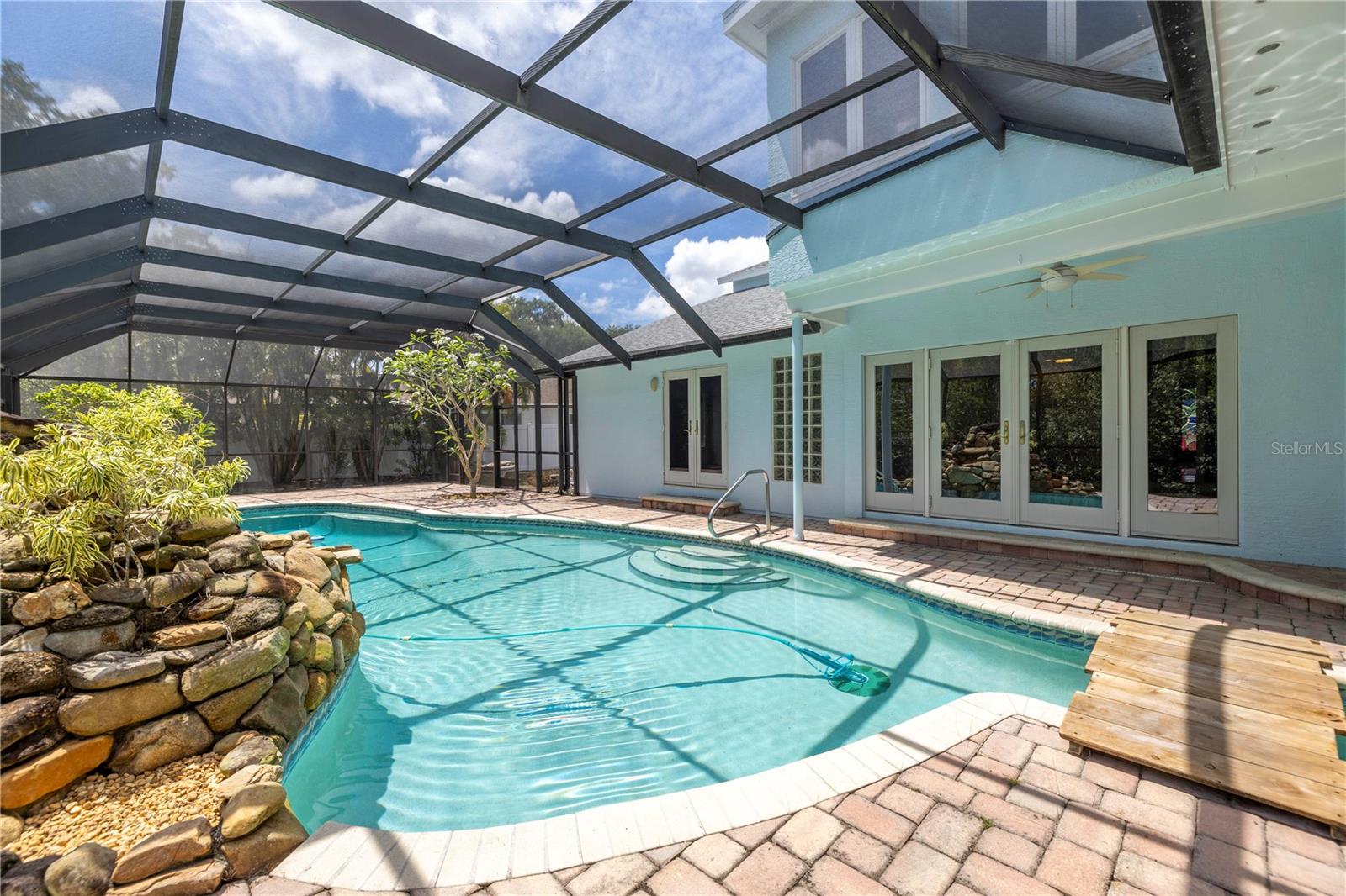 Screen enclosed pool with rock waterfall feature