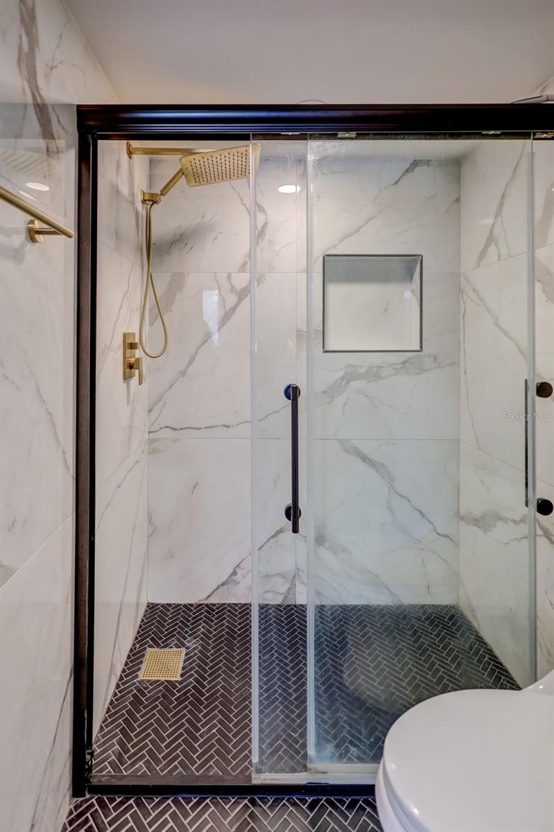 The glass door encloses the shower area, adding a touch of elegance and ease of access.