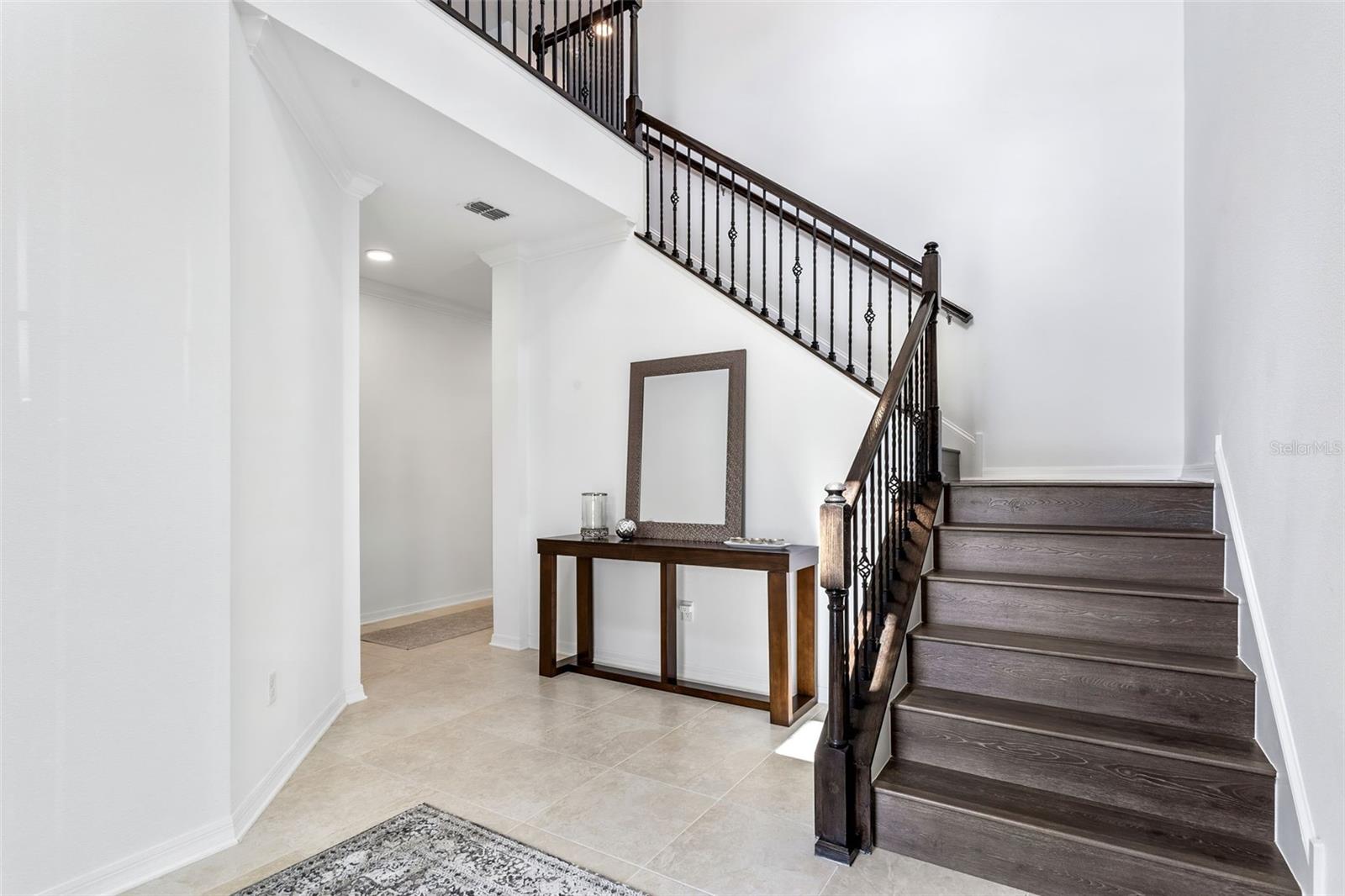 This two story foyer is breathtaking with natural light & wrought iron staircase.