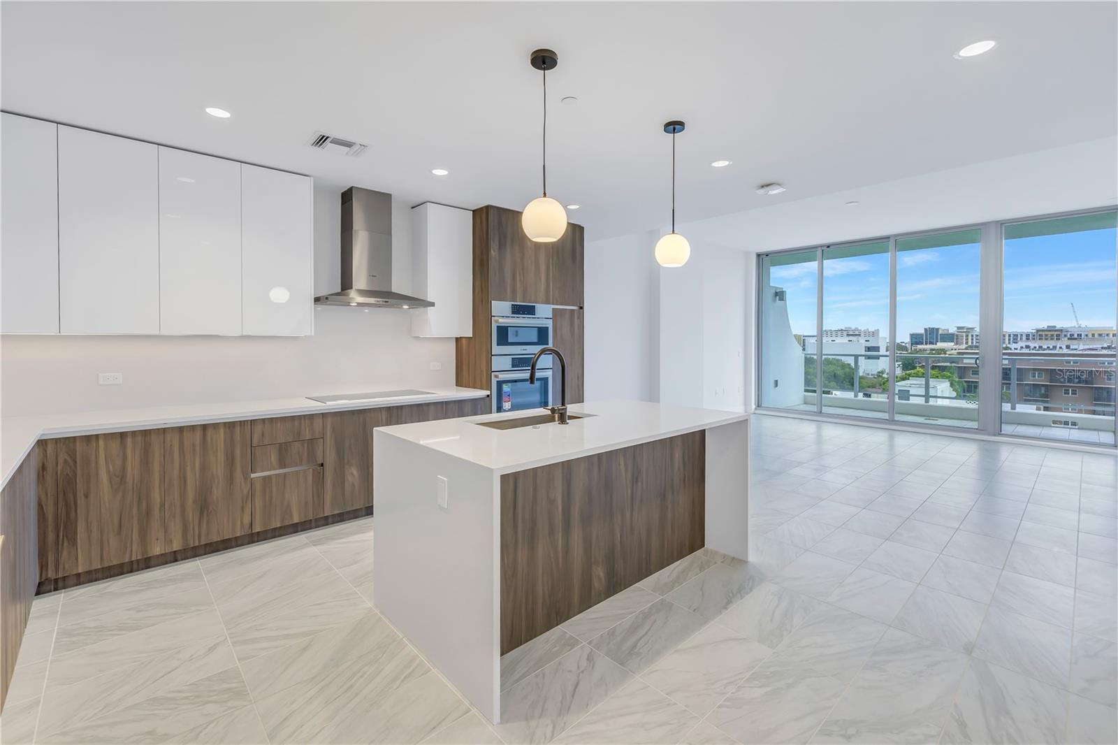 Open layout with Bosch panel-front ready appliances, quartz countertops with quartz up the backsplash, Italkraft cabinetry