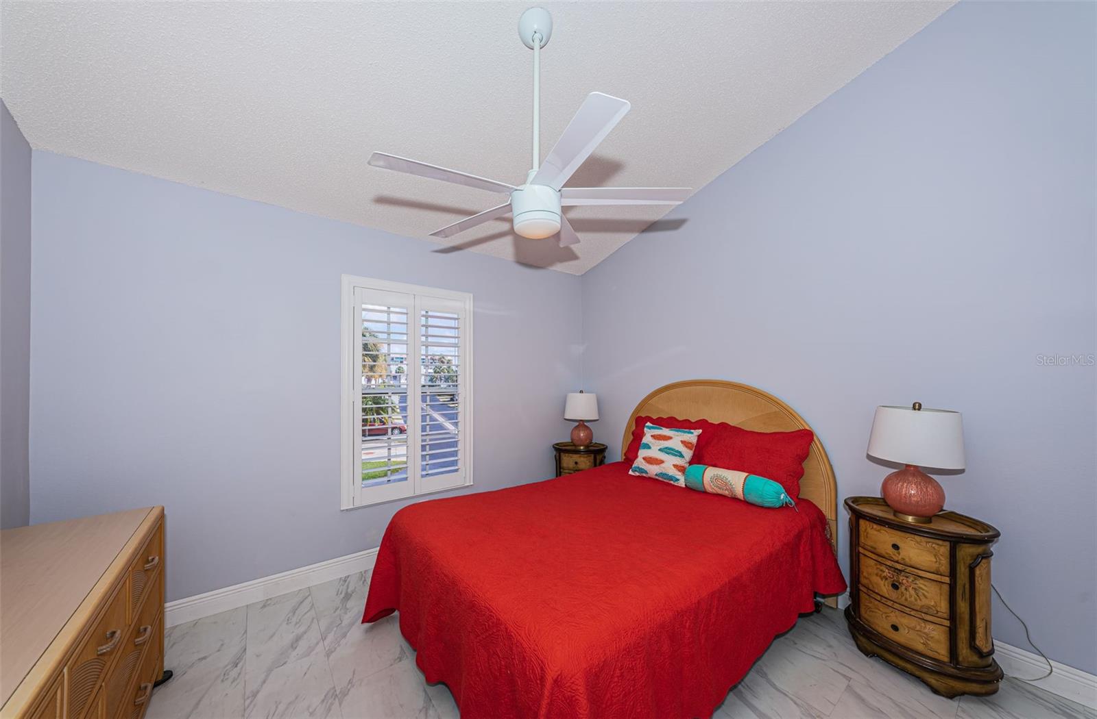 Guest bedroom has cathedral ceilings and plantation shutters.