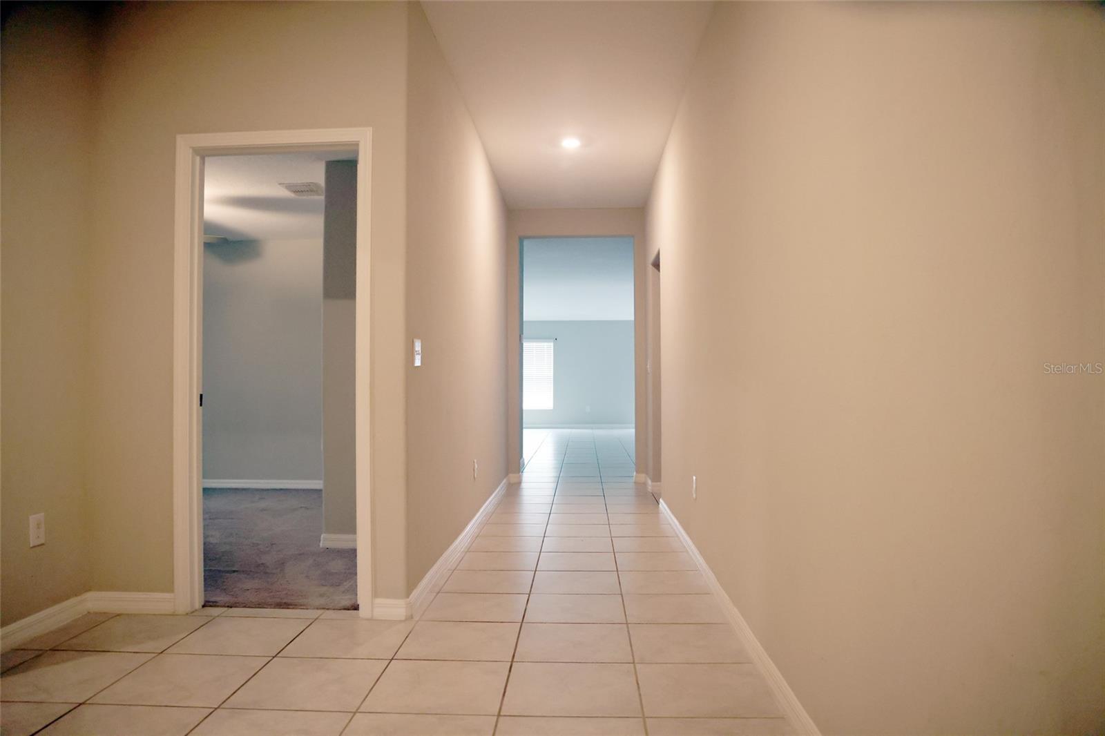 Foyer area with 2nd front bedroom on the left and walkway towards the bonus room, kitchen, living room area