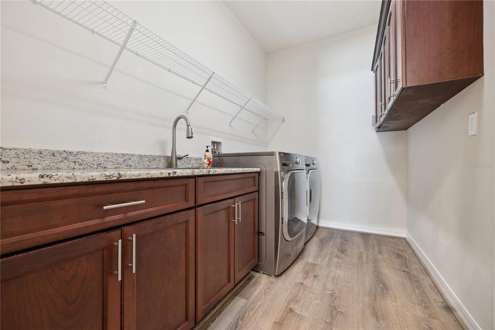 Ample space in laundry room with cabinetry and granite countertops