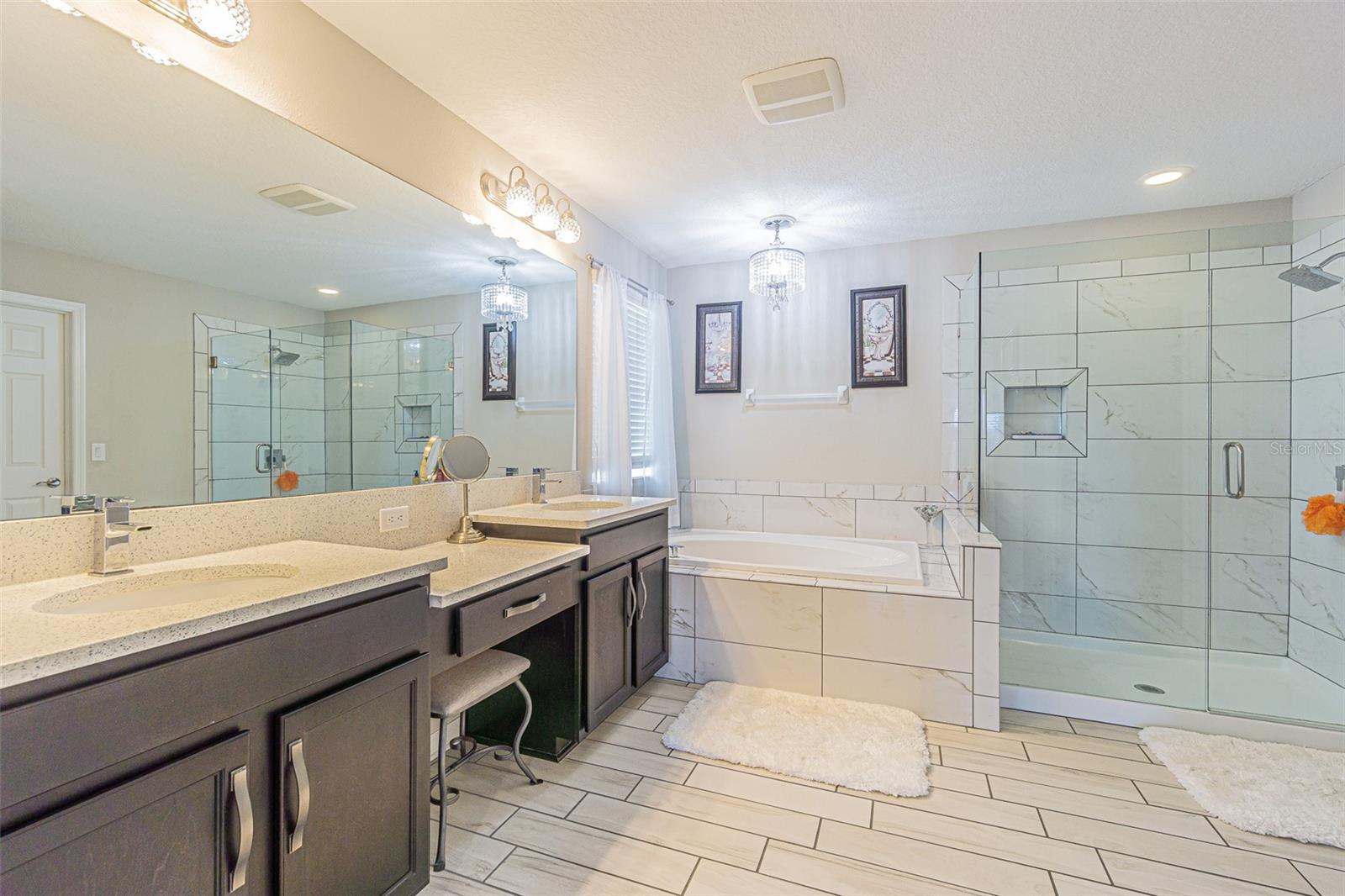 Primary bath with vanity area, frameless glass shower, soaking tub with upgraded chandelier