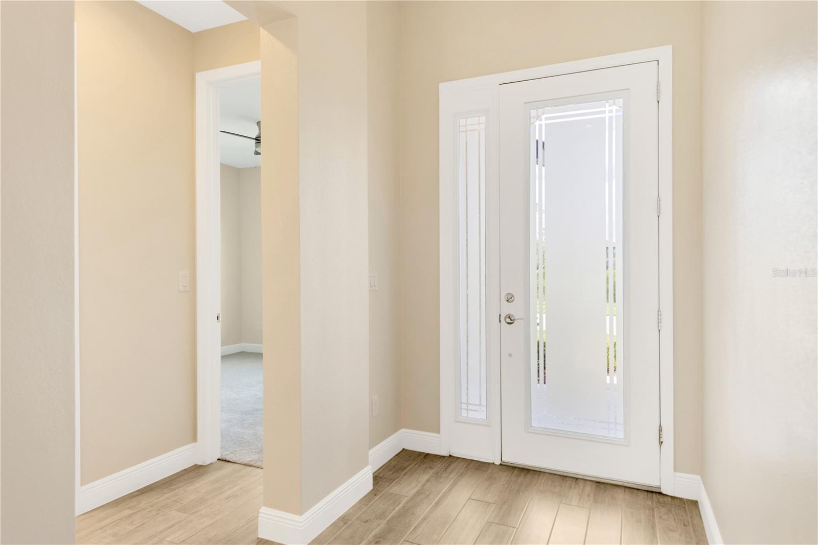 The beautiful foyer with 11’ ceilings gives access to a spacious first bedroom and full guest bathroom.