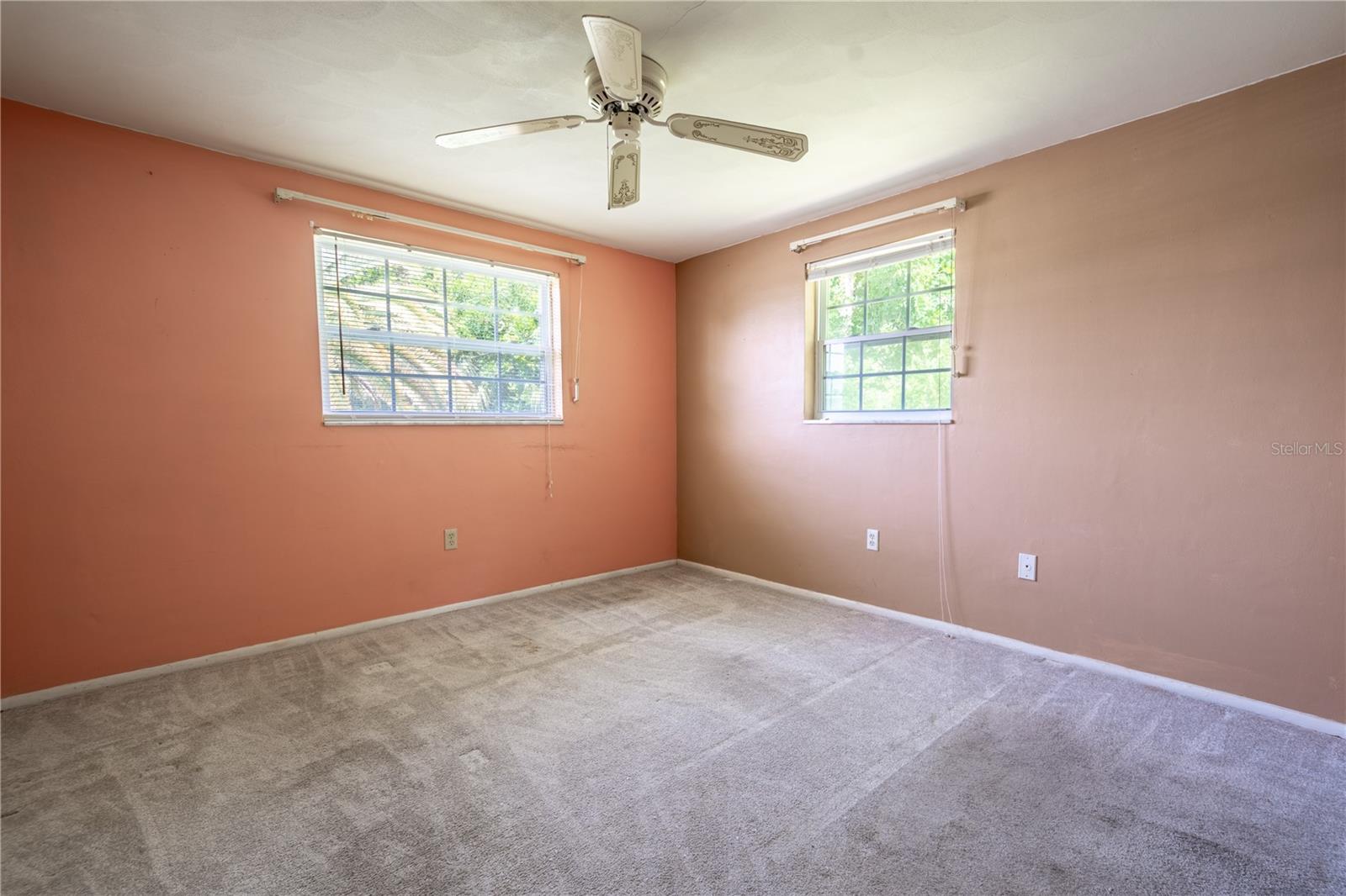 Bedroom 2 features neutral tone carpet, a ceiling fan, and a built-in cedar closet.