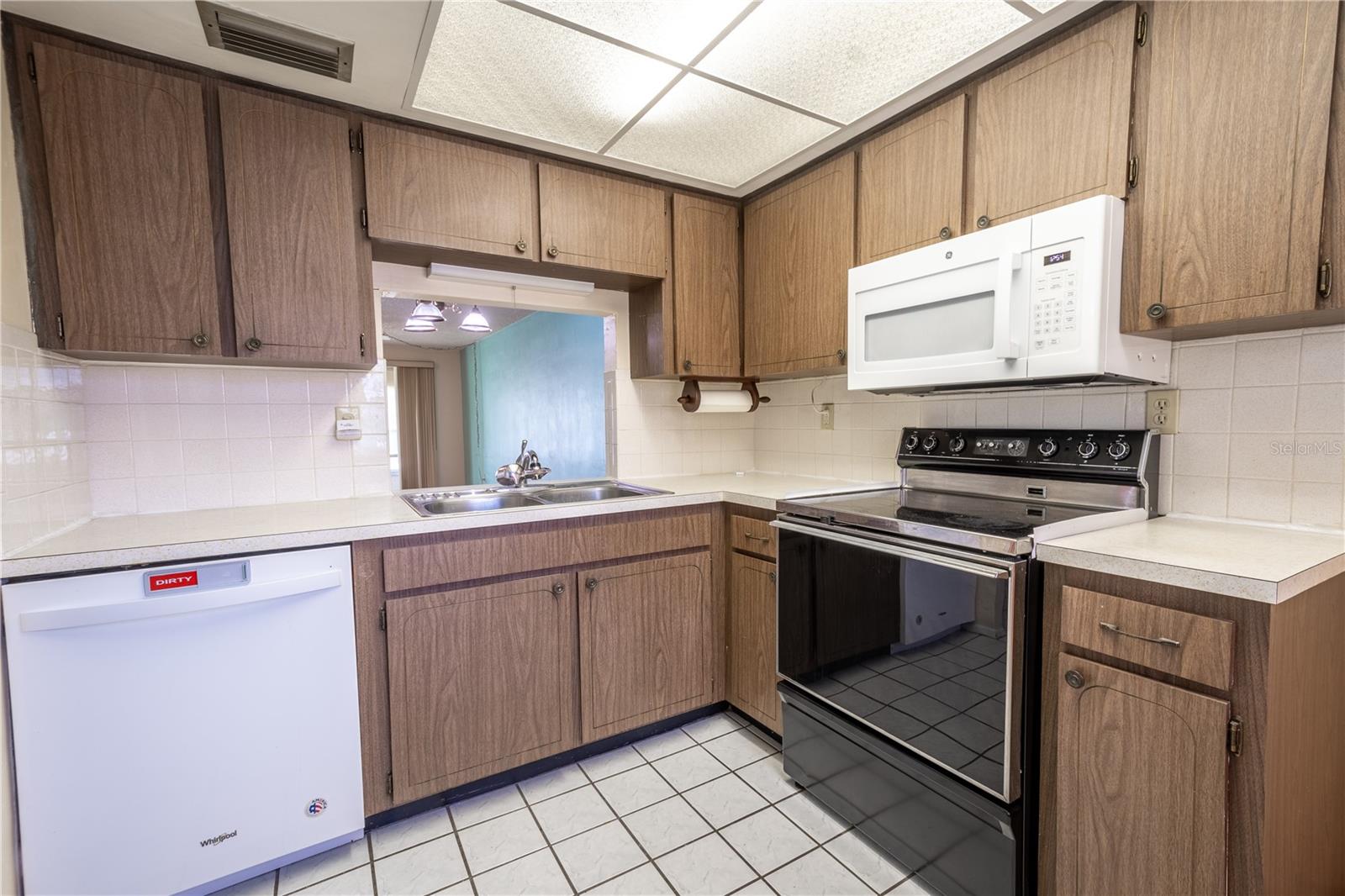 The kitchen has plenty of cabinet and counter space, overhead lighting, a ceramic tile flooring and a passthrough to the dining room.