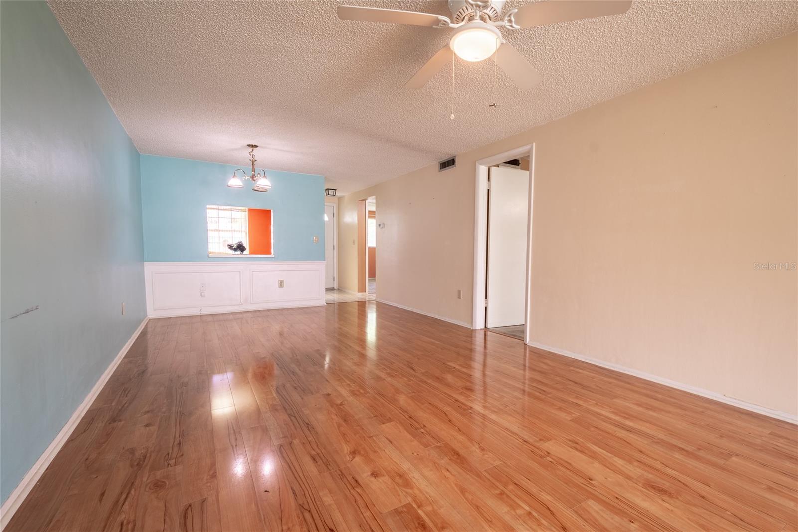 The living room is open to the Florida room. It features like new wood laminate flooring and a ceiling fan for year-round comfort.