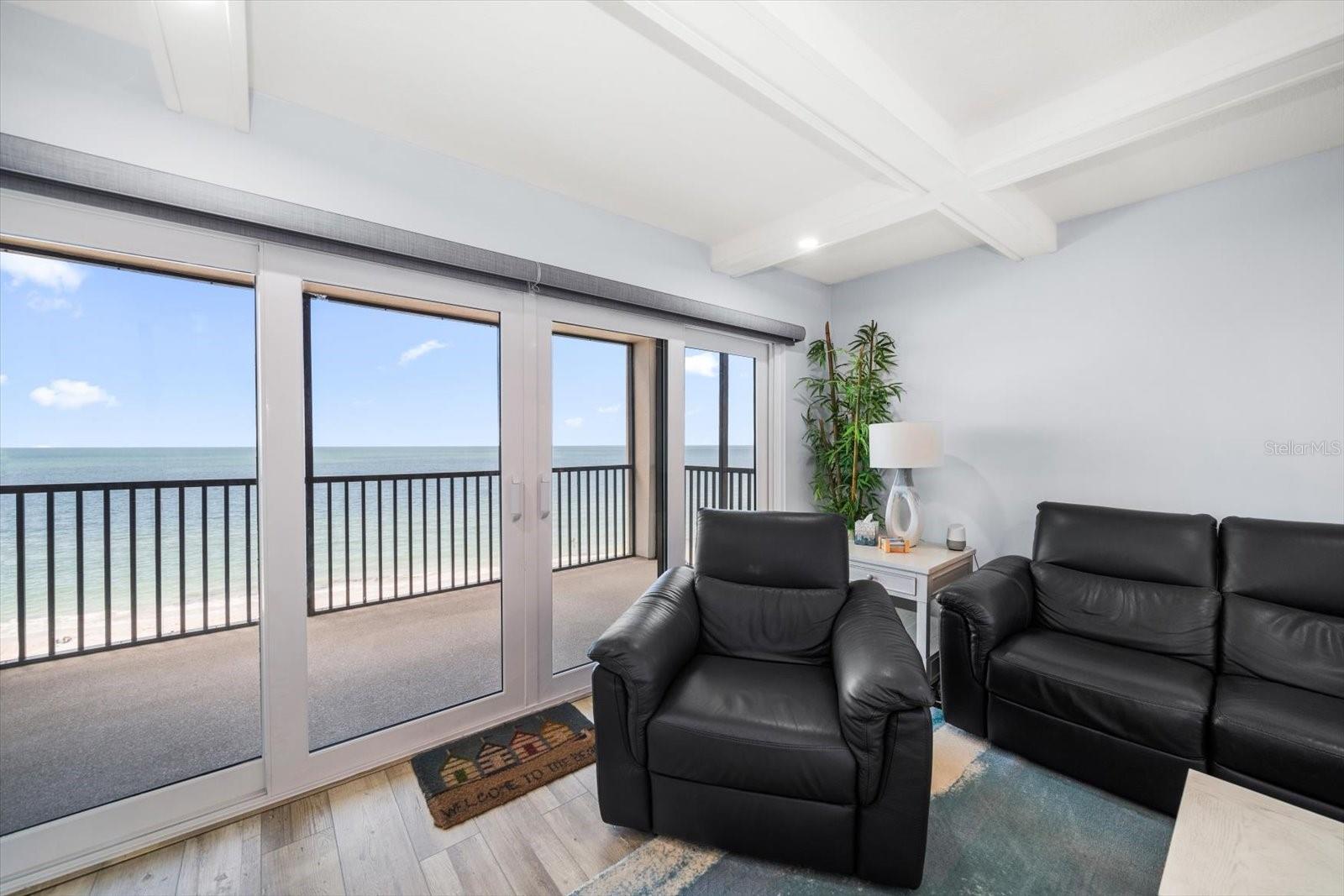 Great room area. Lovely furnishings, coffered ceilings, motorized shades and new impact glass sliders... so many upgrades!