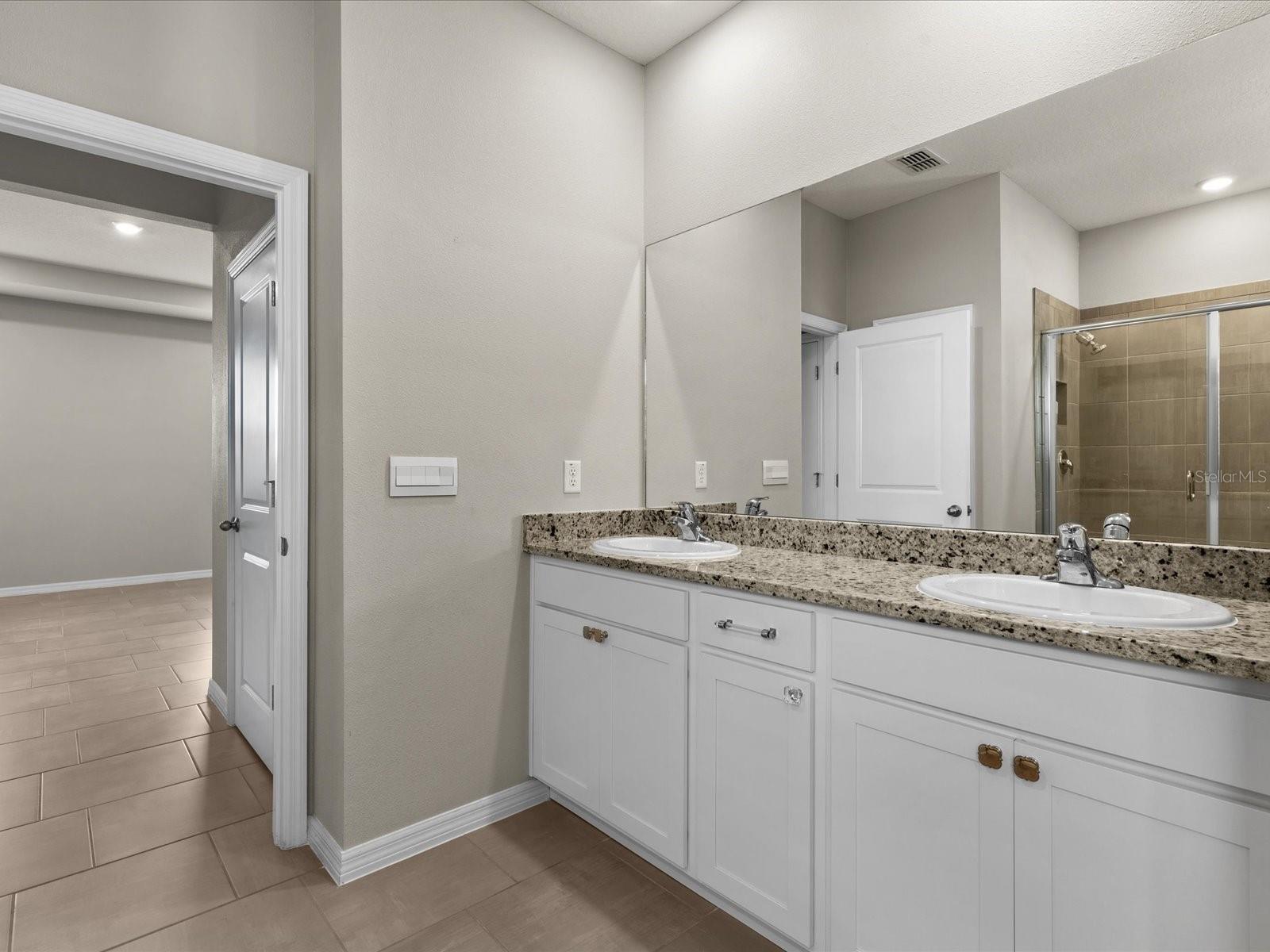 Primary Ensuity Bath featuring dual vanities and walk in closets