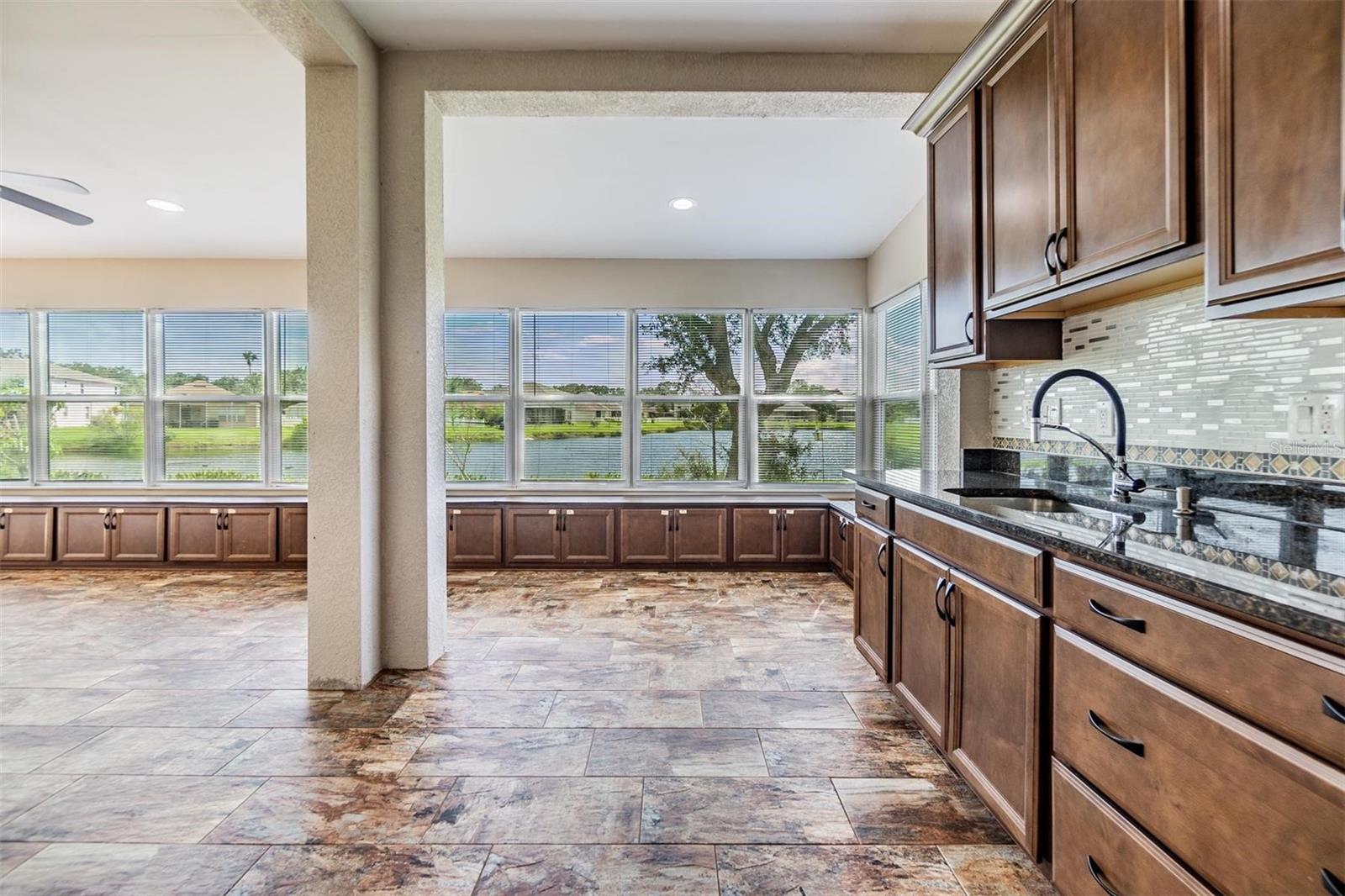 Huge back patio with a full kitchen, lots of cabinet space, tile flooring, ceiling fans and granite countertops.