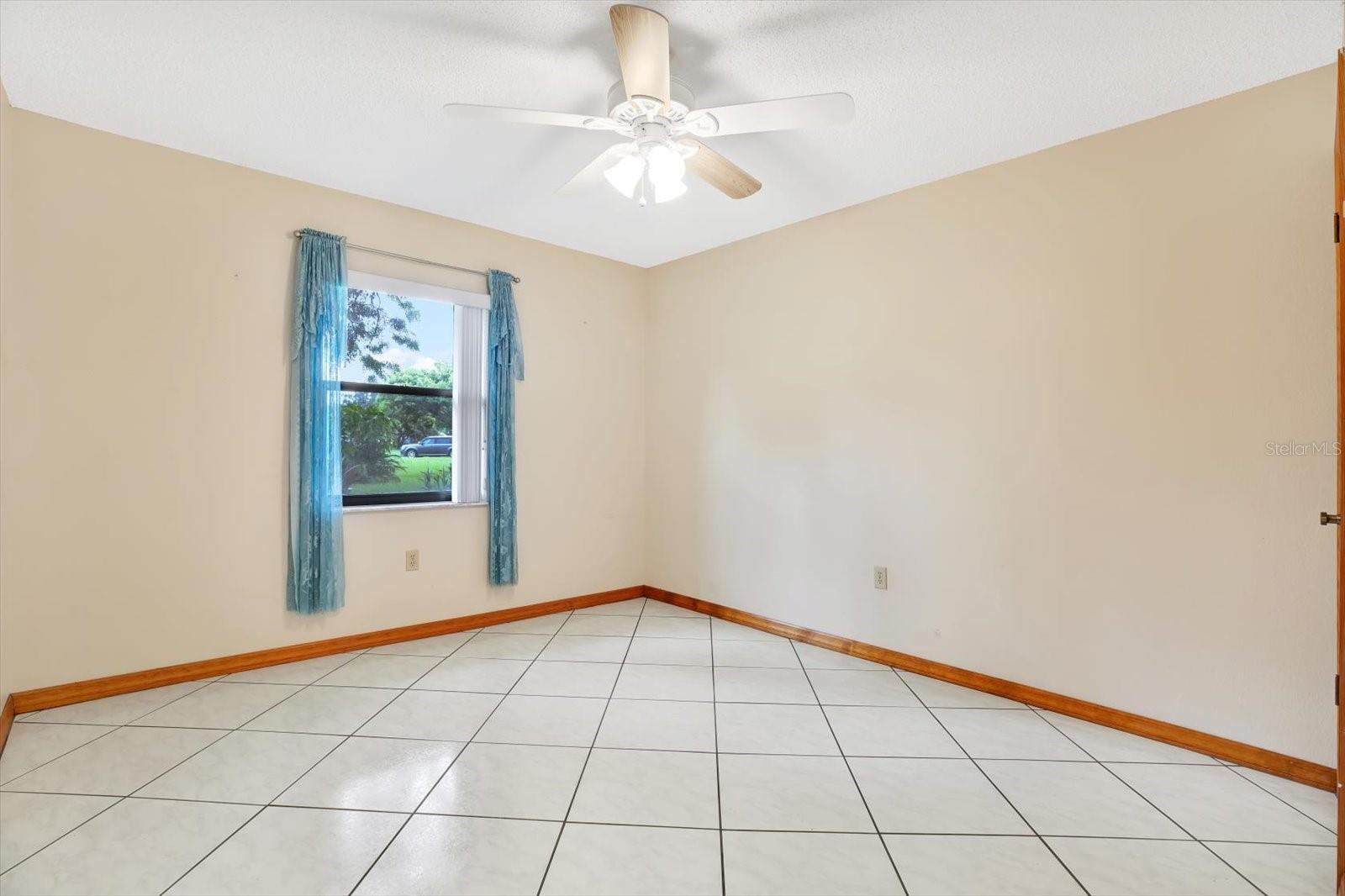 2nd Bedroom  with tile floor, walk-in closet and a combo ceiling fan/light fixture