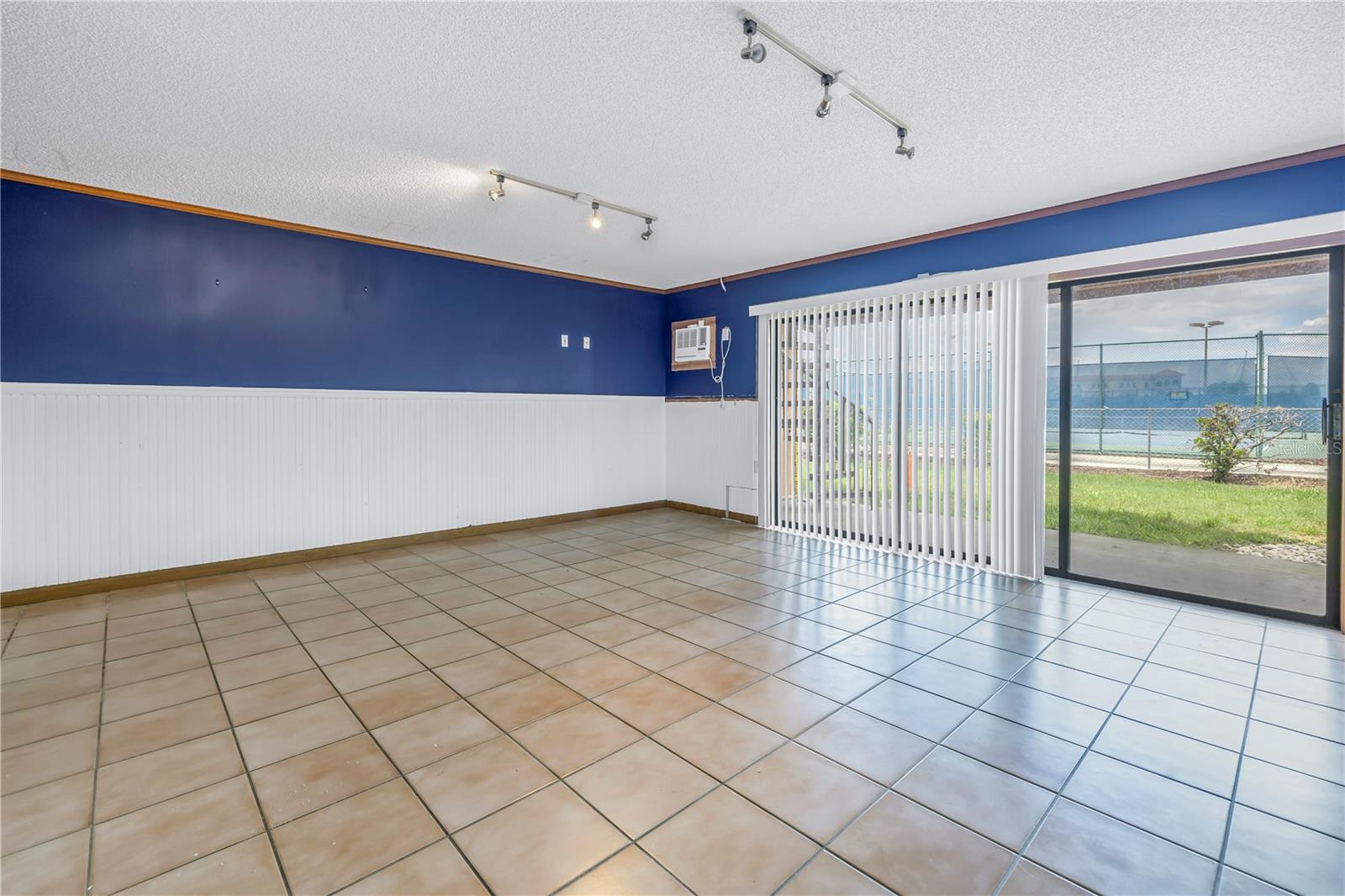 Flex room with tile floors leads to back patio.