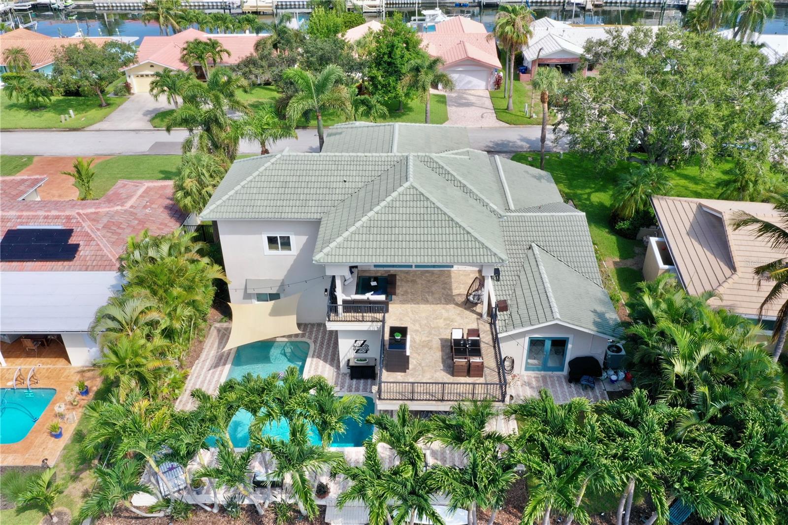 Back of waterfront pool home with views of primary suite balcony.