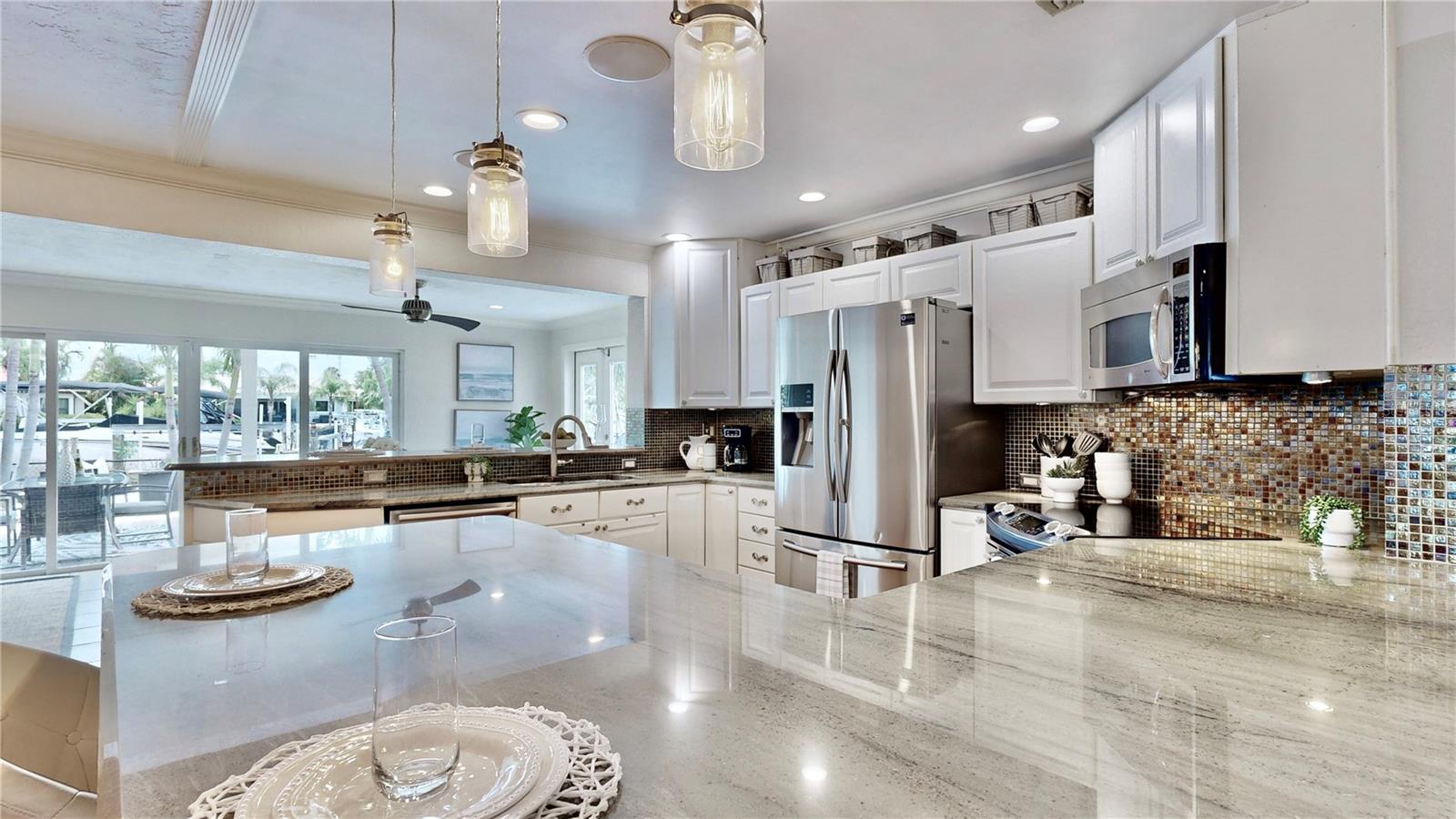 Gorgeous waterfront & pool views from the kitchen. Massive granite countertops, perfect for prepping and cooking.