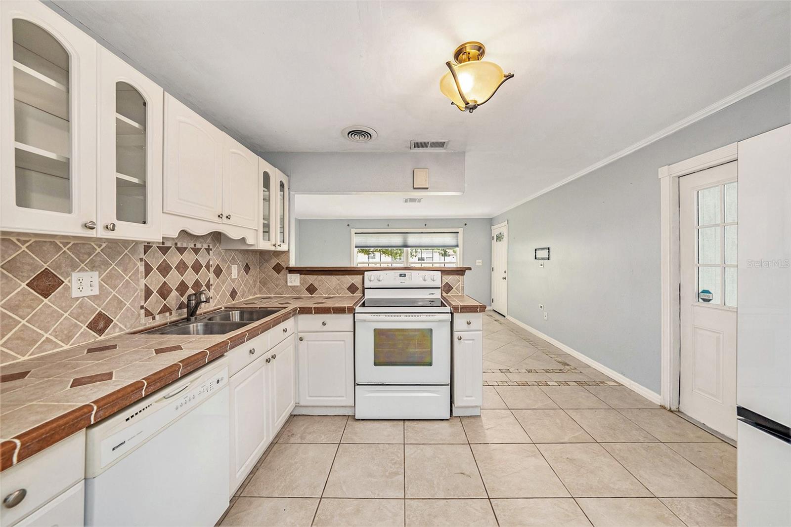 Cute kitchen with real wood cabinetry, tiled backsplash and counters, and breakfast bar.