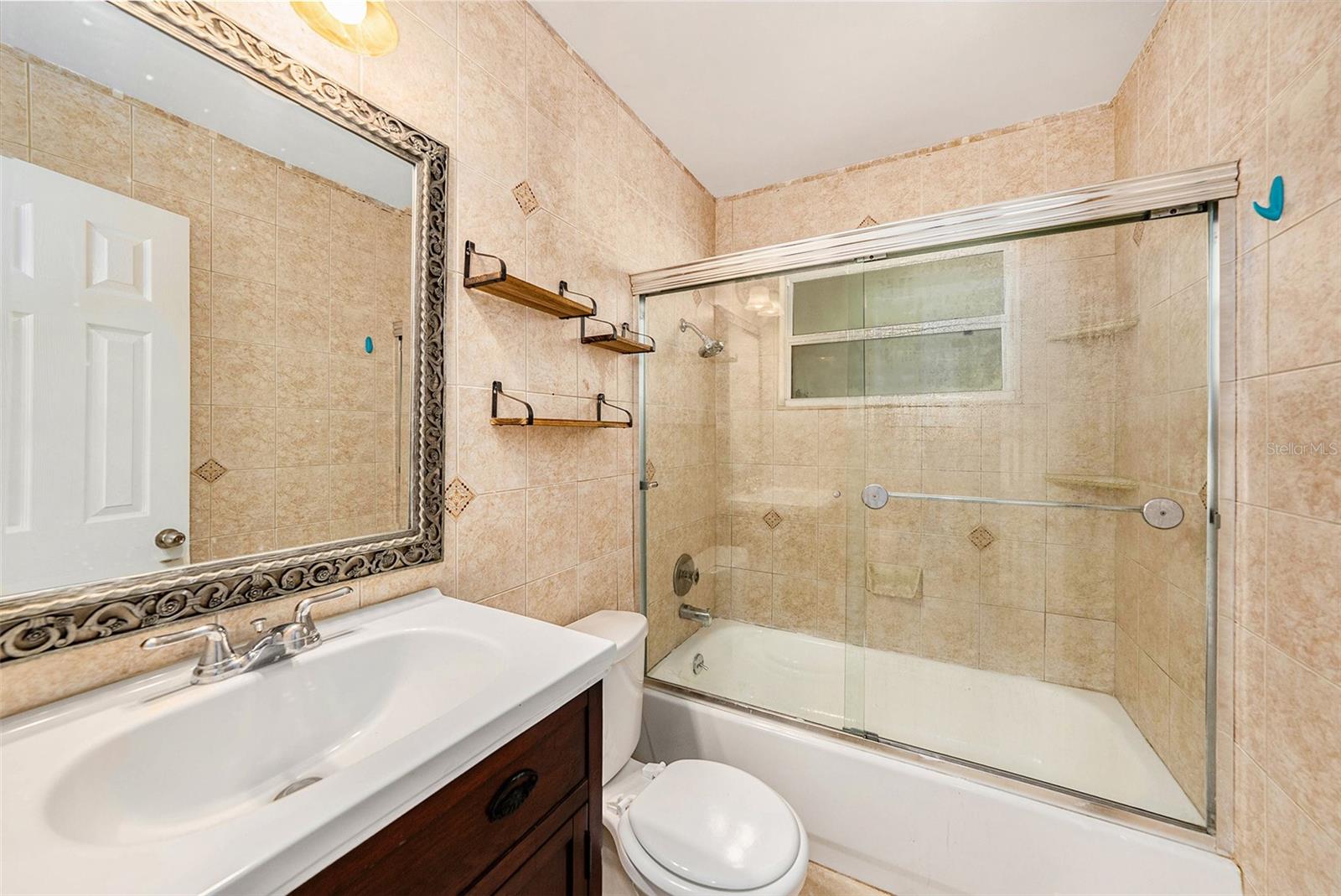 Bathroom at the front of the home with glass shower doors and wood vanity.