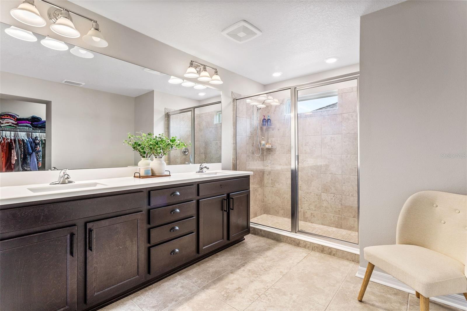 Primary bathroom with dual vanities and walk in shower