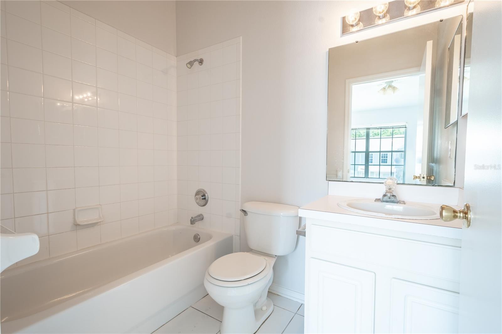 Bathroom 2 features a tiles tub with shower, ceramic tile floor, and a mirrored vanity with storage.