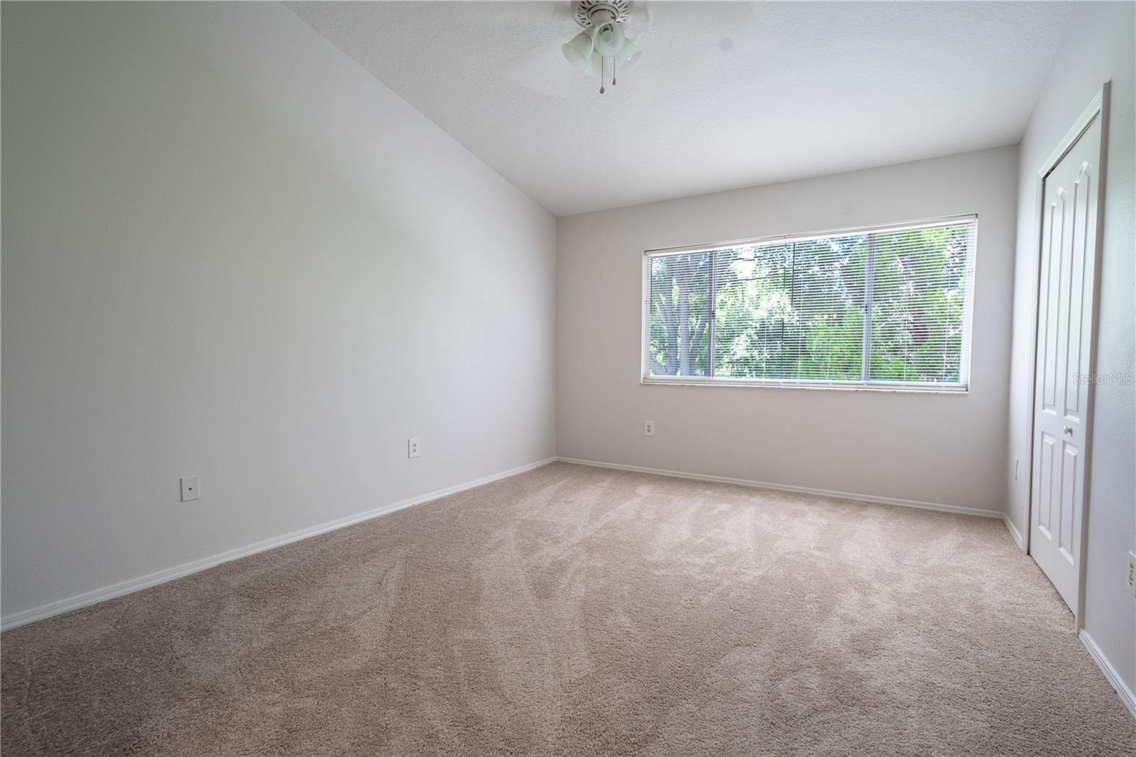 Primary bedroom features vaulted ceiling, large picture window. built-in closet and a ceiling fan with light kit.