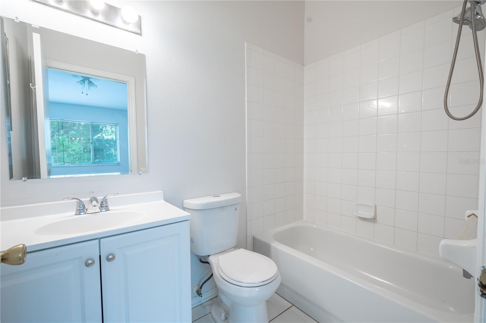 Primary ensuite features a tiled tub with shower, ceramic tile floor and a mirrored vanity with storage.