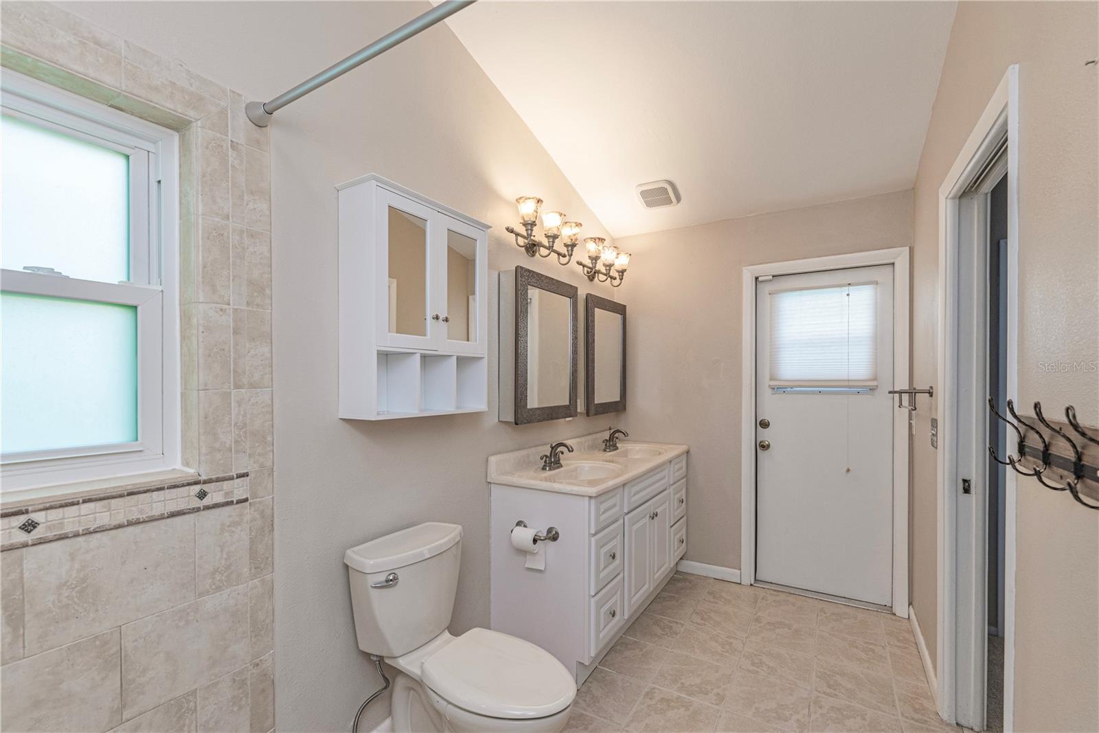 Primary bathroom has double sinks and door to pool lanai.